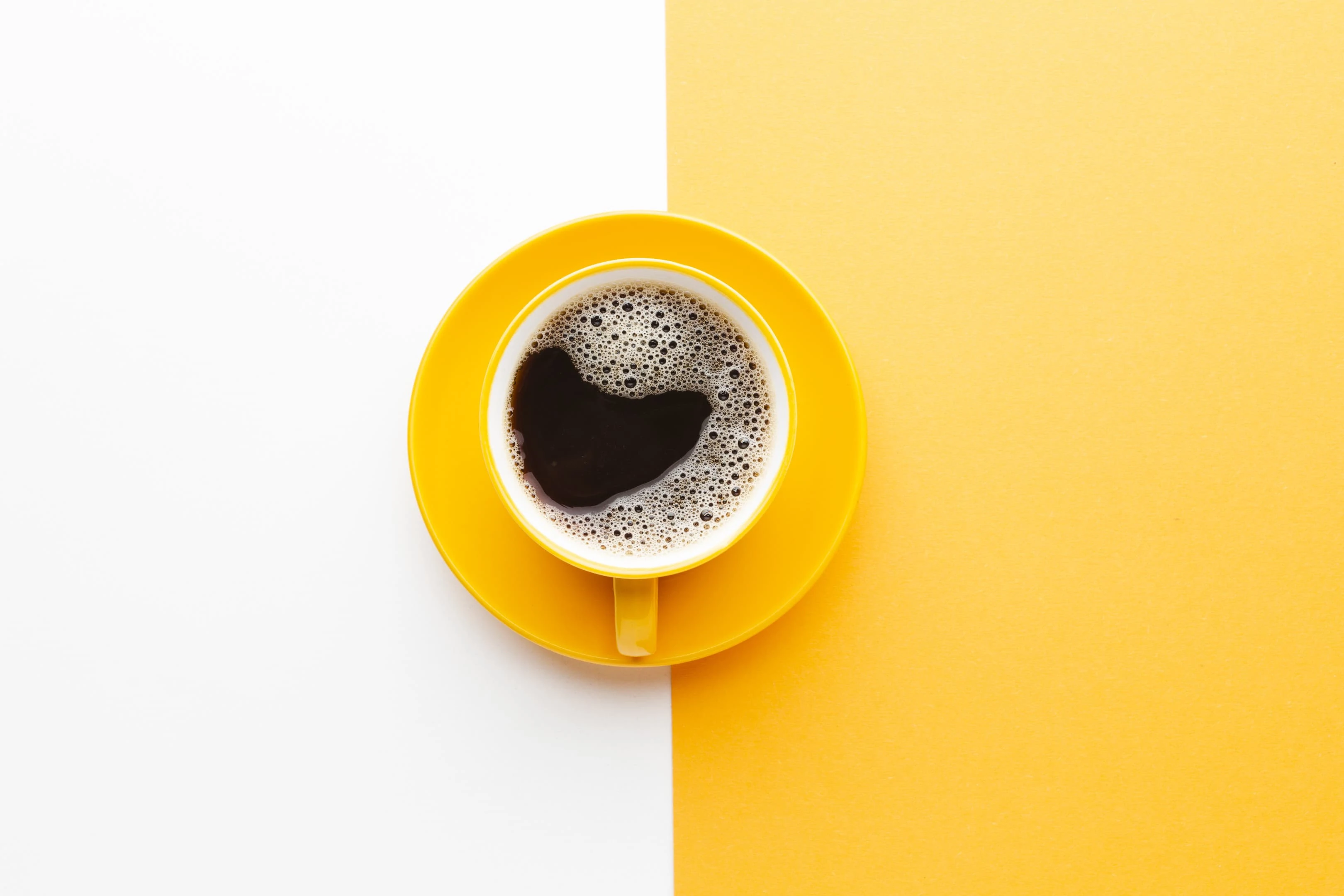 Top view fresh cup of coffee on white and yellow background