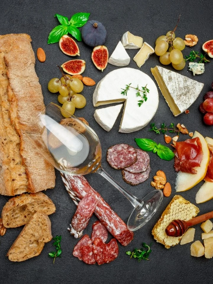 Various types of cheese, meat, fruits and wine on table