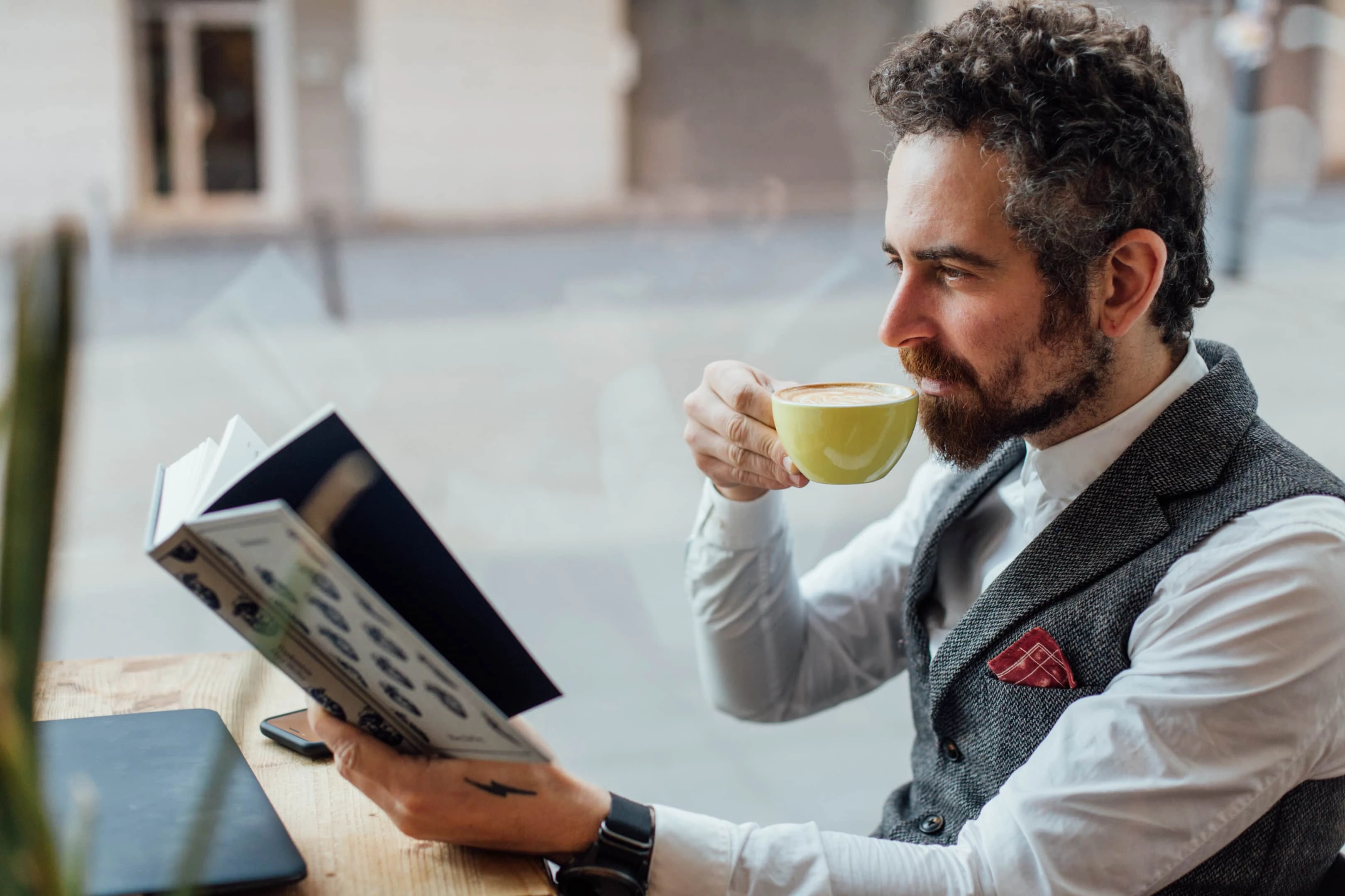 adult middle aged man sips coffee while reading interesting book