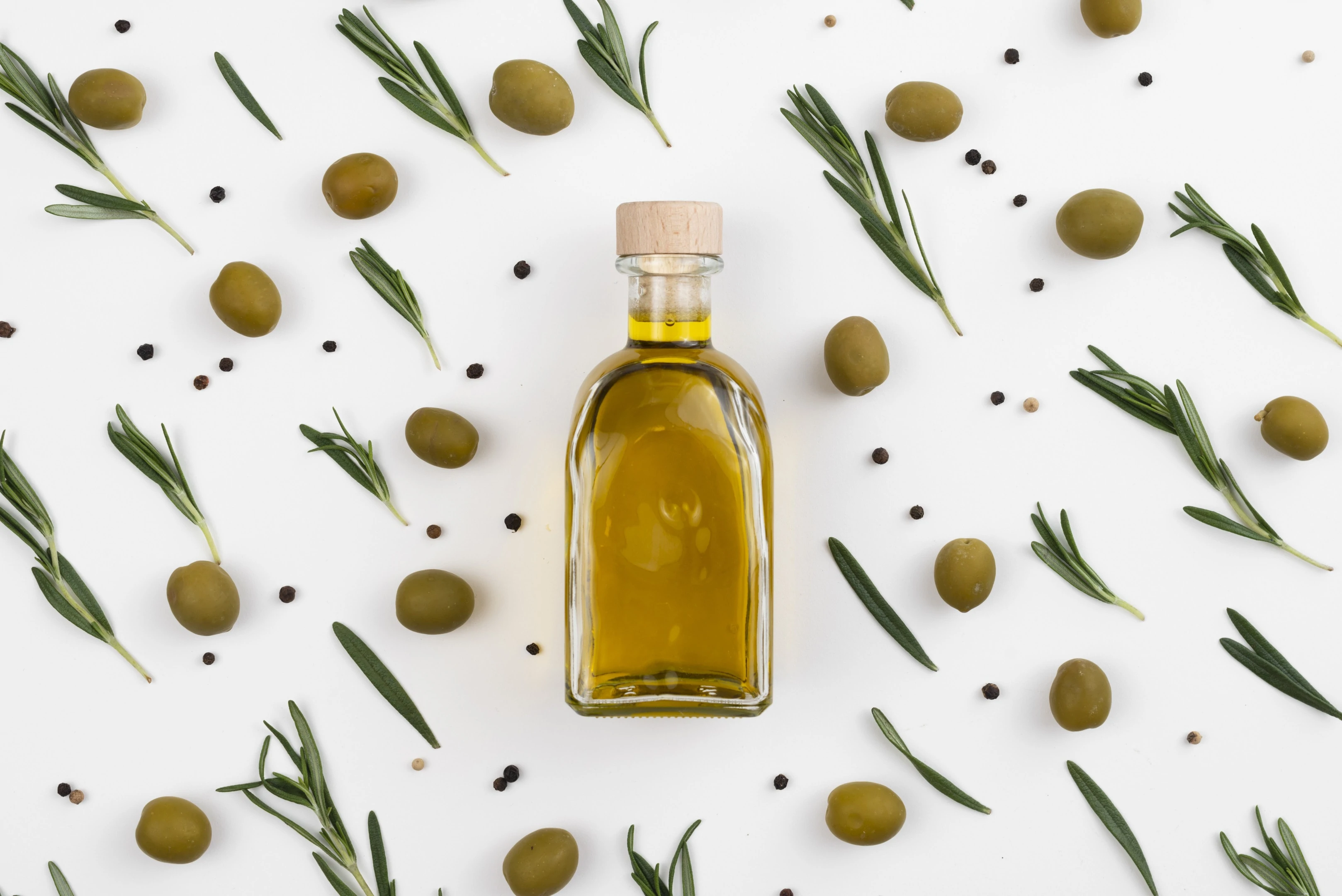 Arrangement of olive leaves and olive oil bottle on white background