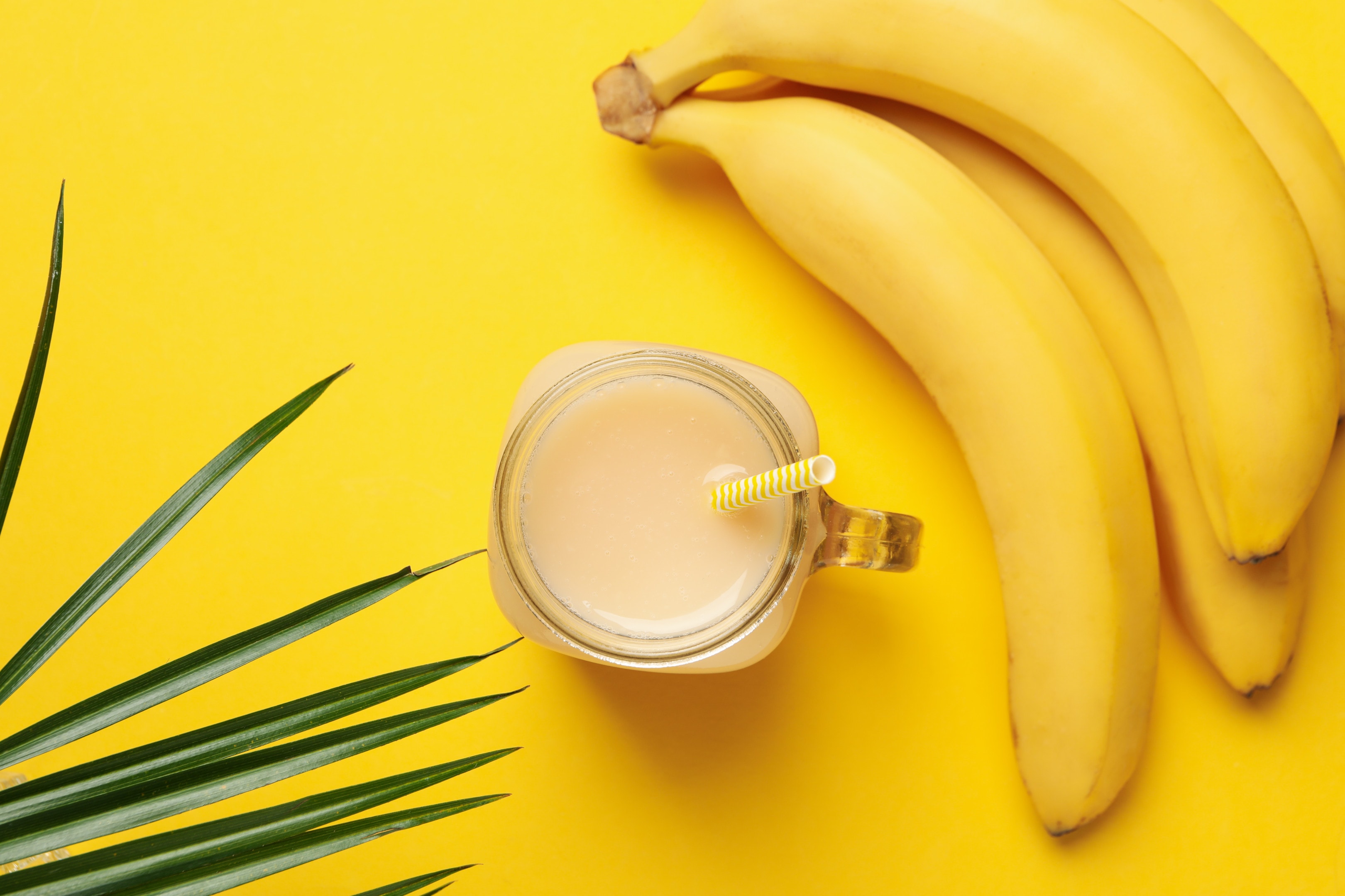 Bananas and banana juice on yellow background