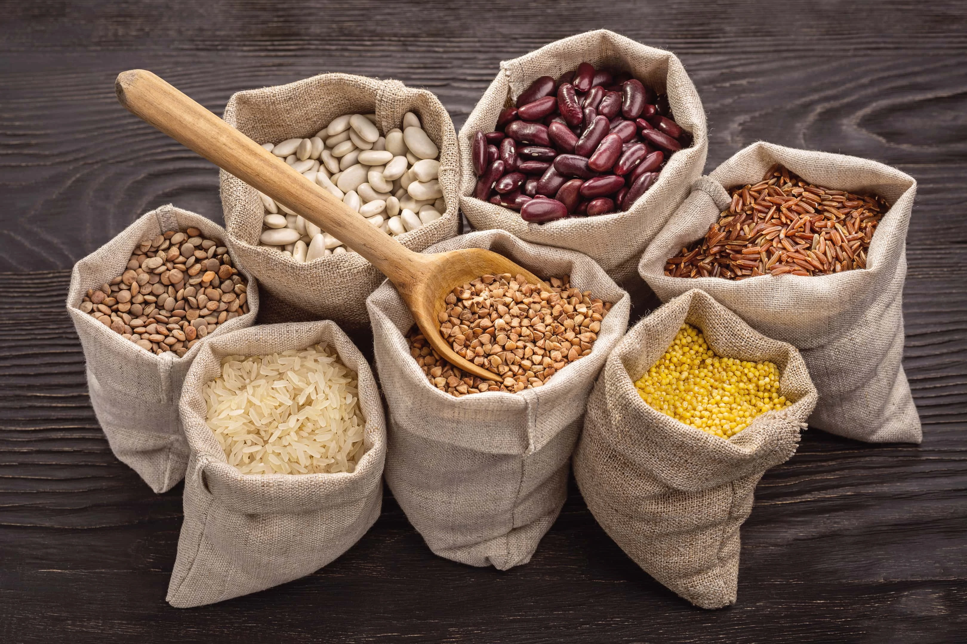 Beans and legumes in bags on wooden background