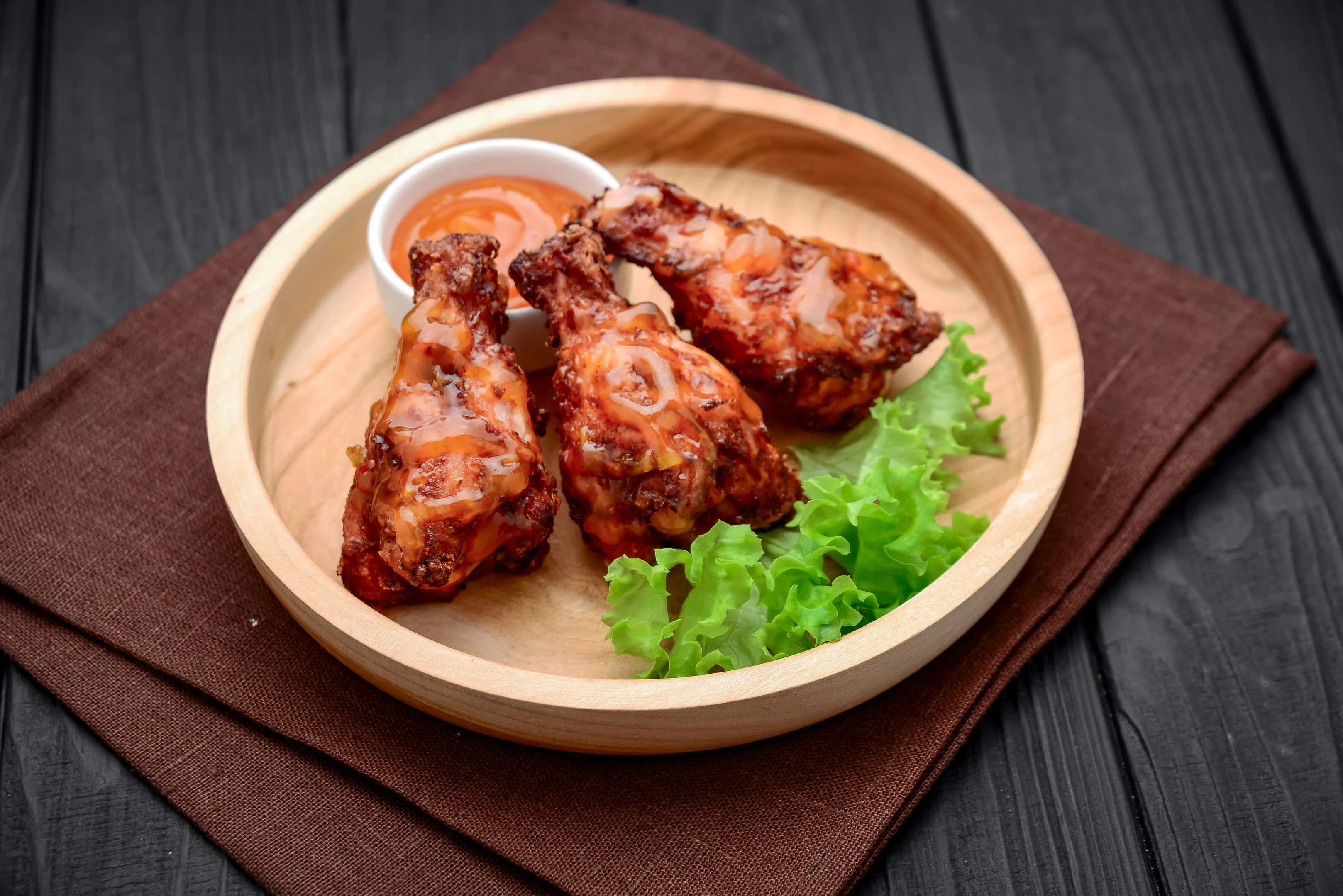 Caribbean jerk chicken wings with spicy chili sauce on wooden plate