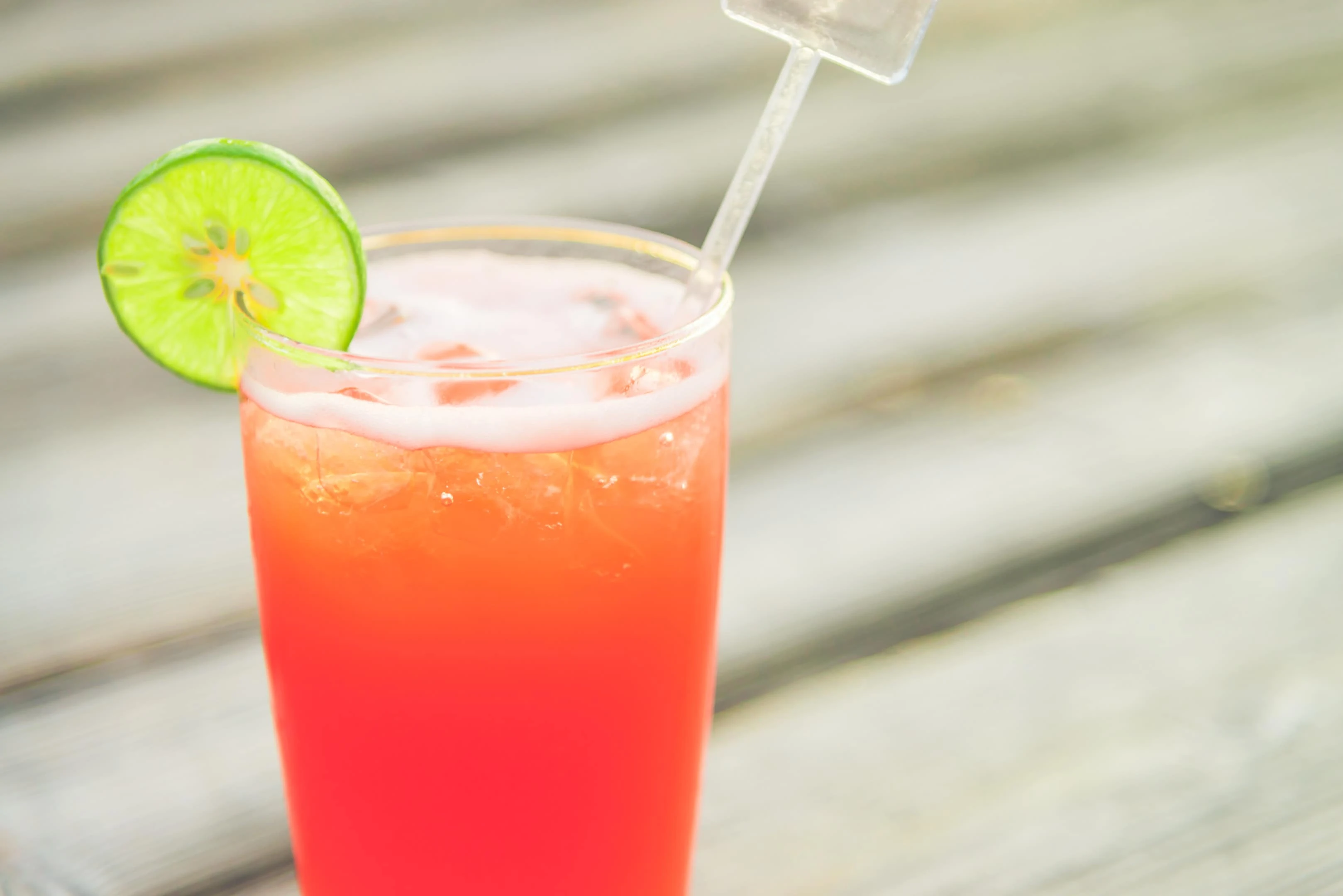 Caribbean rum punch with lime on wooden table