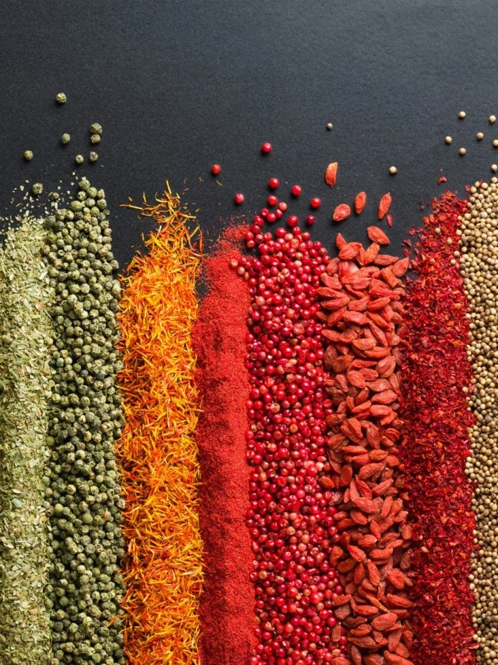 Colorful collection of spices and herbs on black table