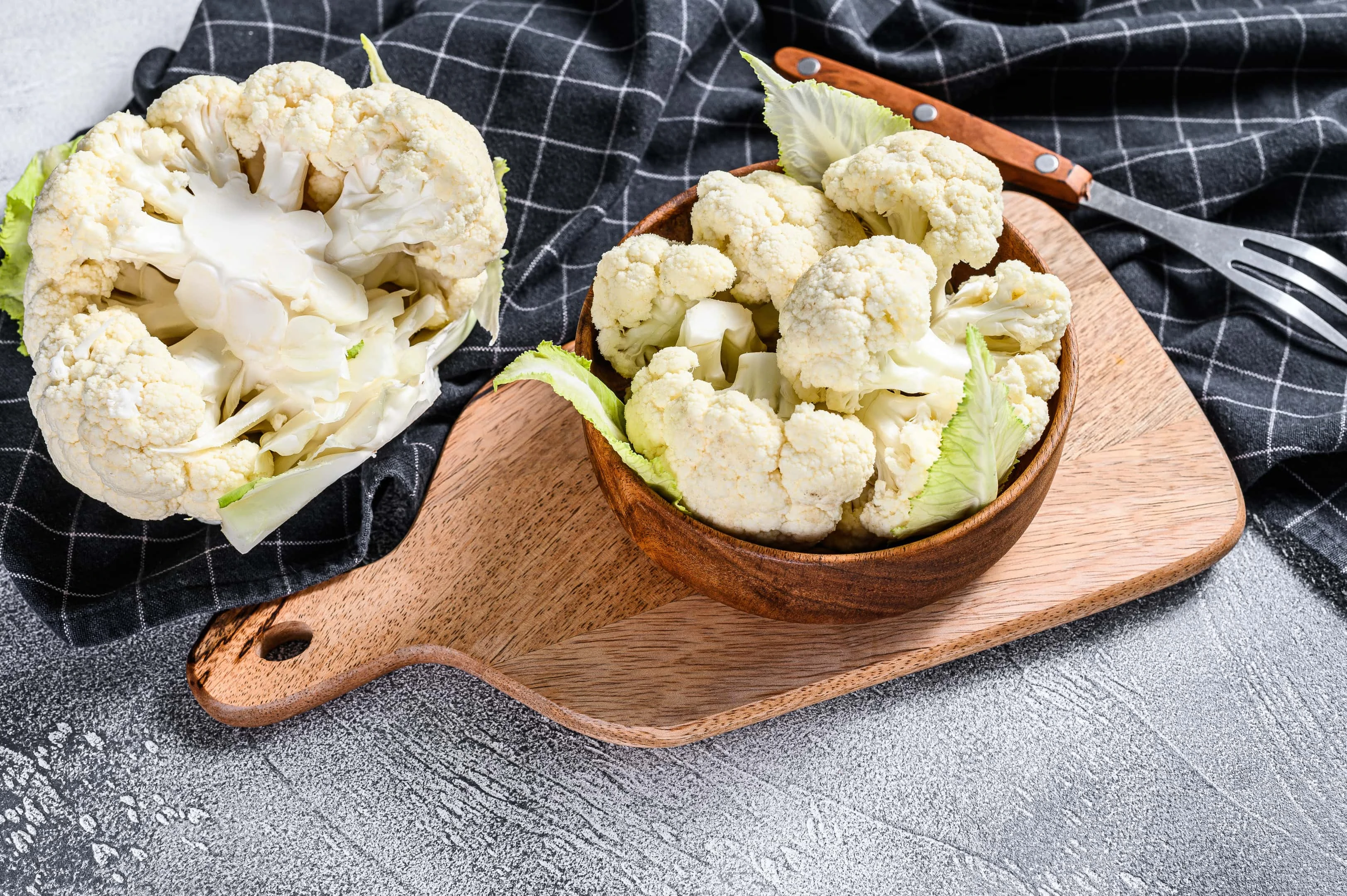 Fresh cauliflower cut into small pieces in wooden bowl
