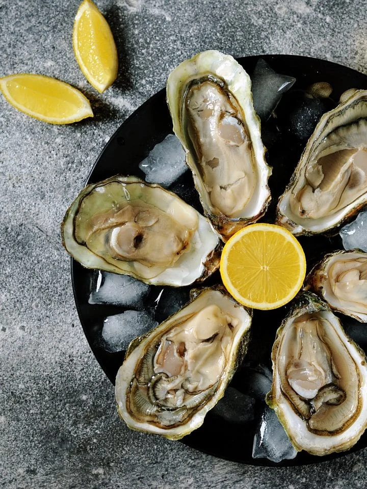 Fresh oysters with lemon slices on plate