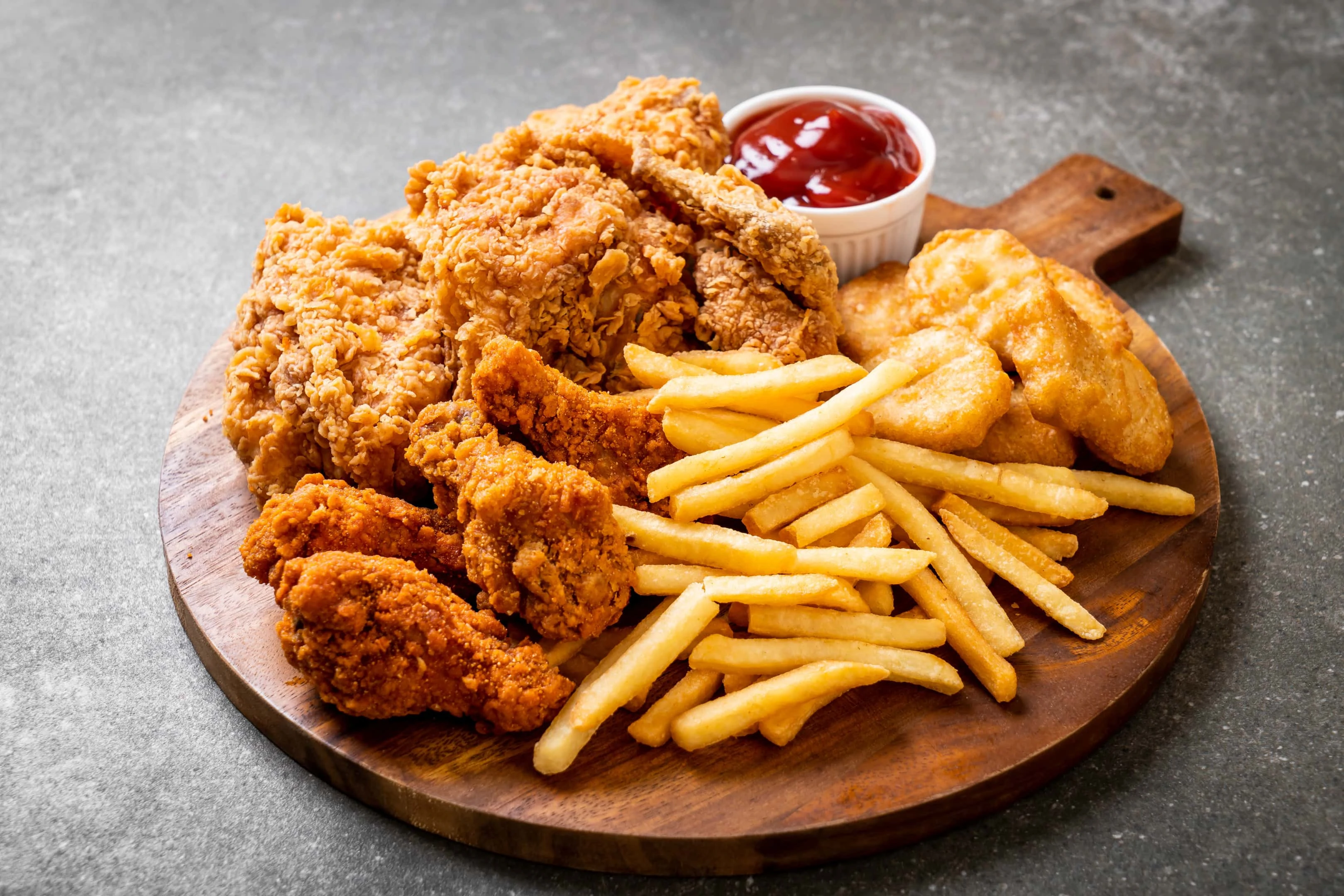 Fried chicken with french fries and nuggets on wooden board
