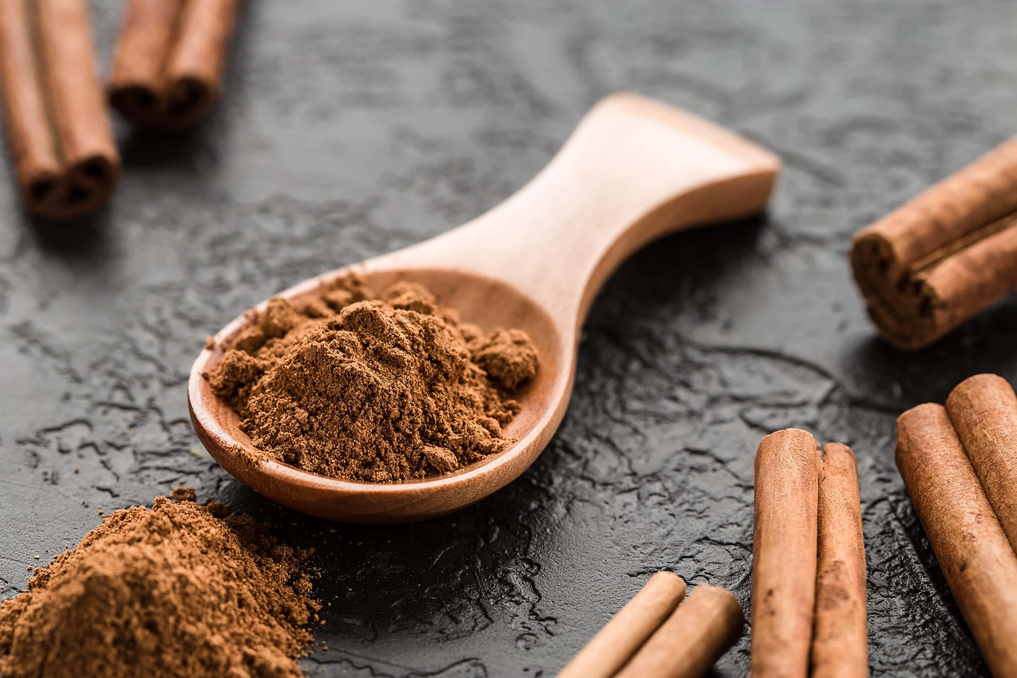 Ground cinnamon powder in wooden spoon