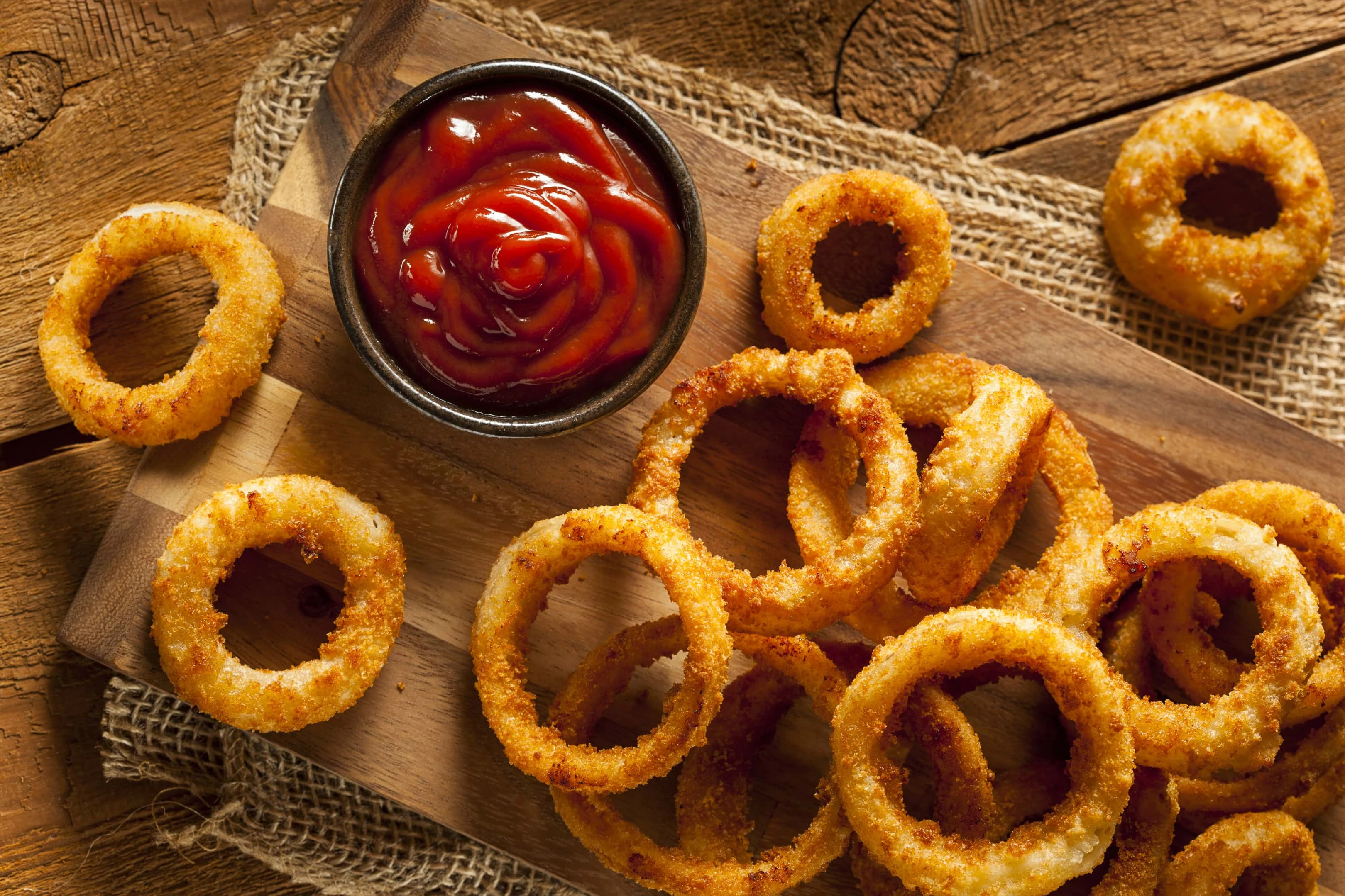 Homemade crunchy fried onion rings on wooden board