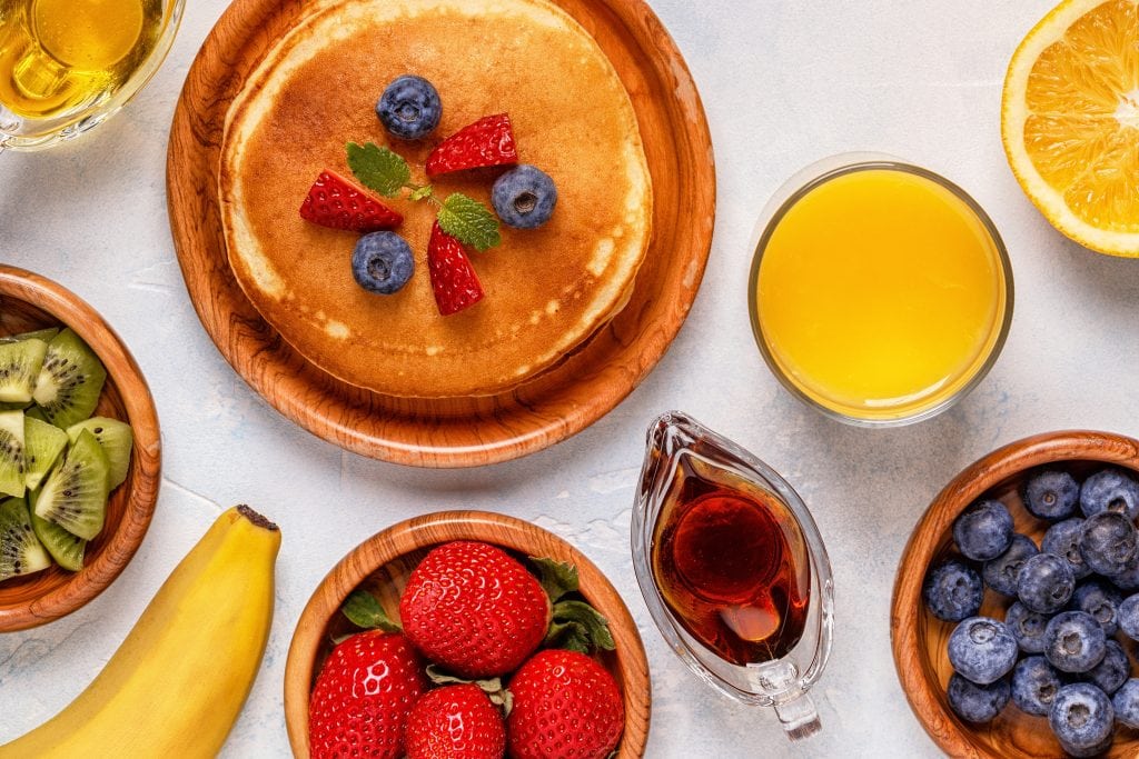 Pancakes with fruit and maple syrup top view