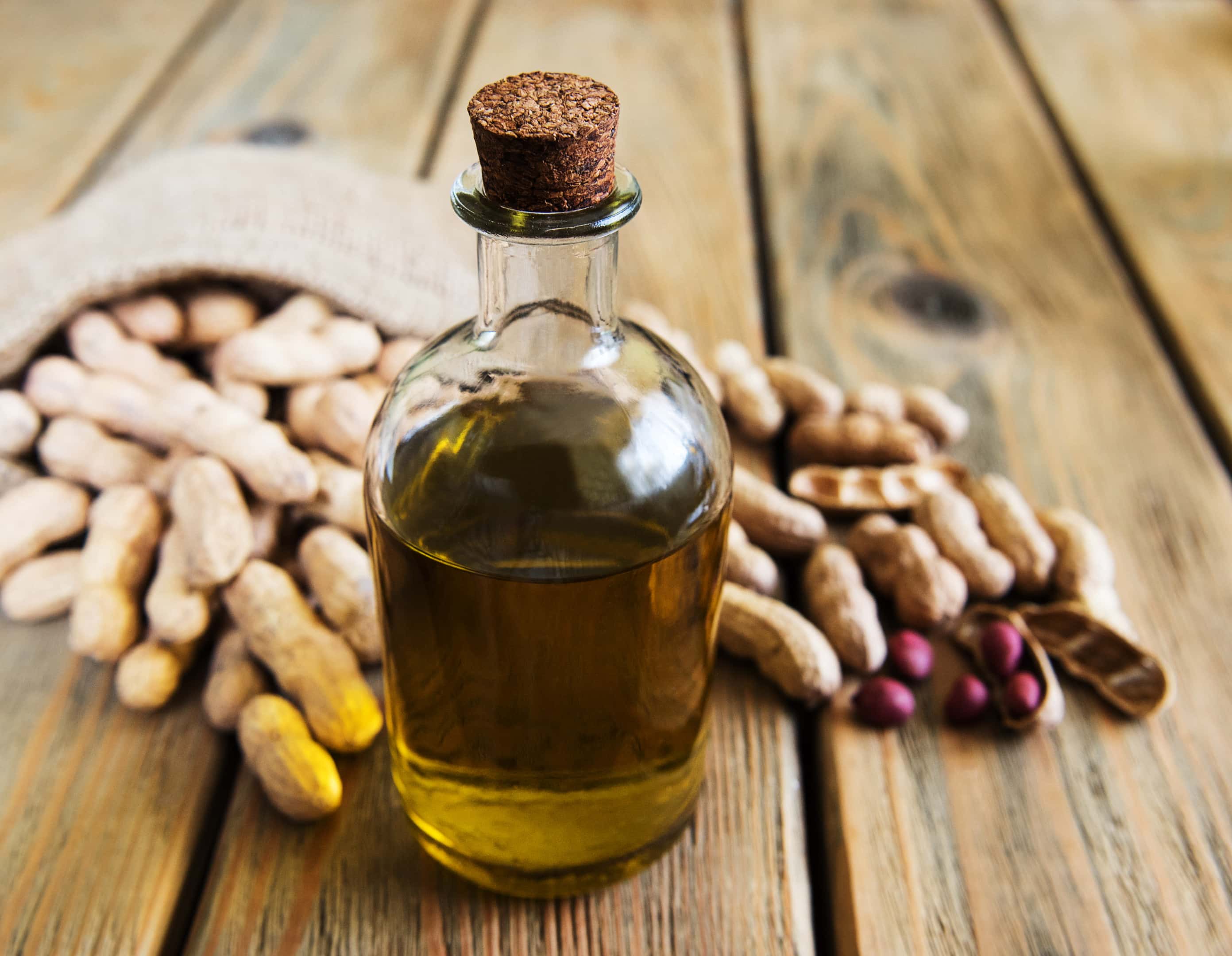 Peanut oil and peanuts on wooden table