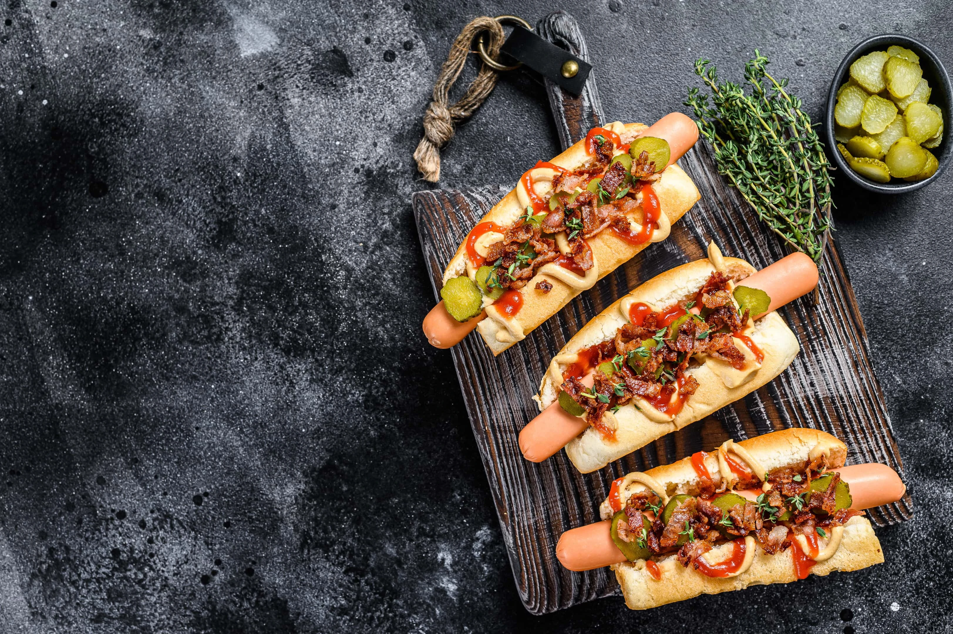 Processed hot dogs with different toppings on dark wooden background