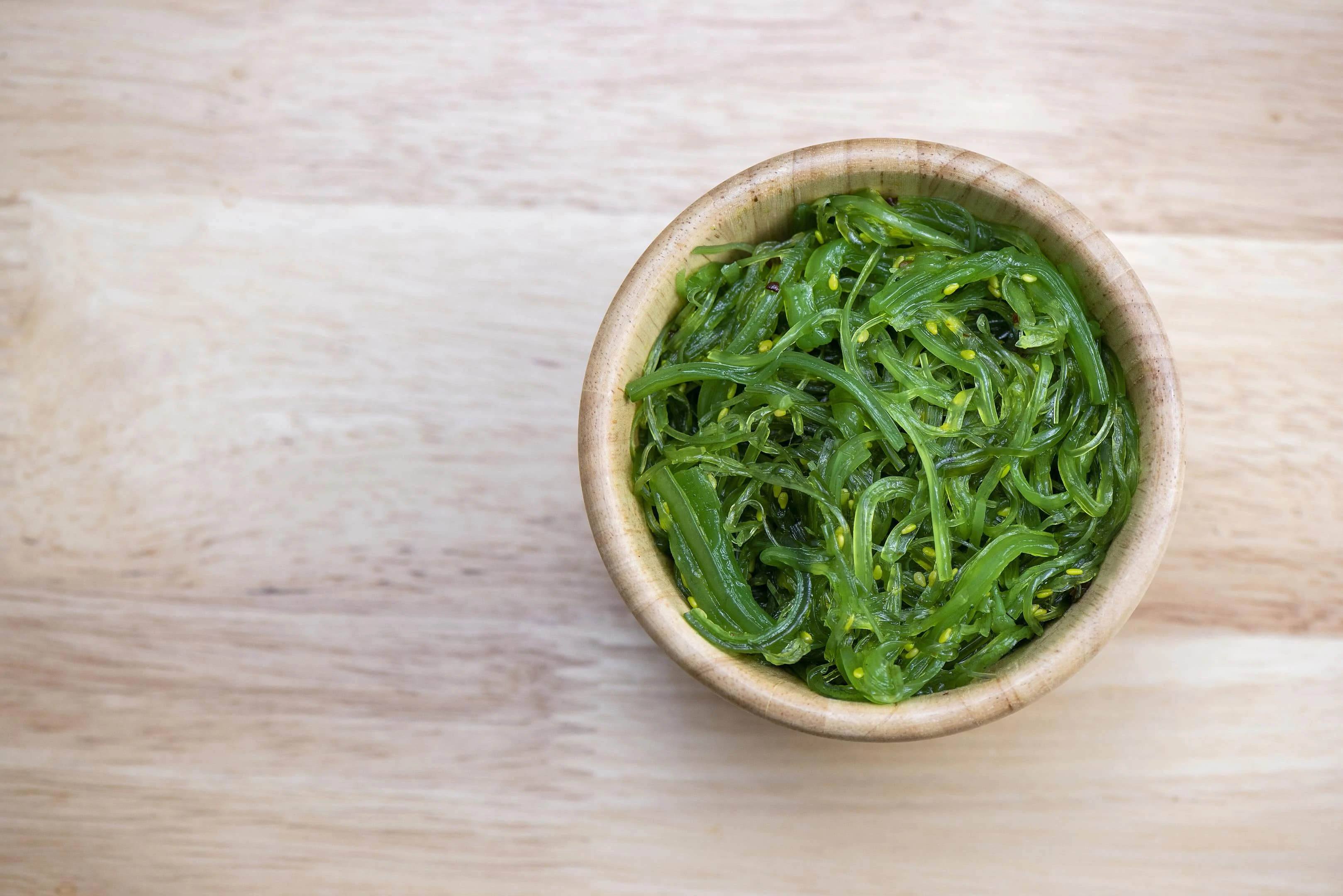 Seaweed salad in wooden bowl on wooden table