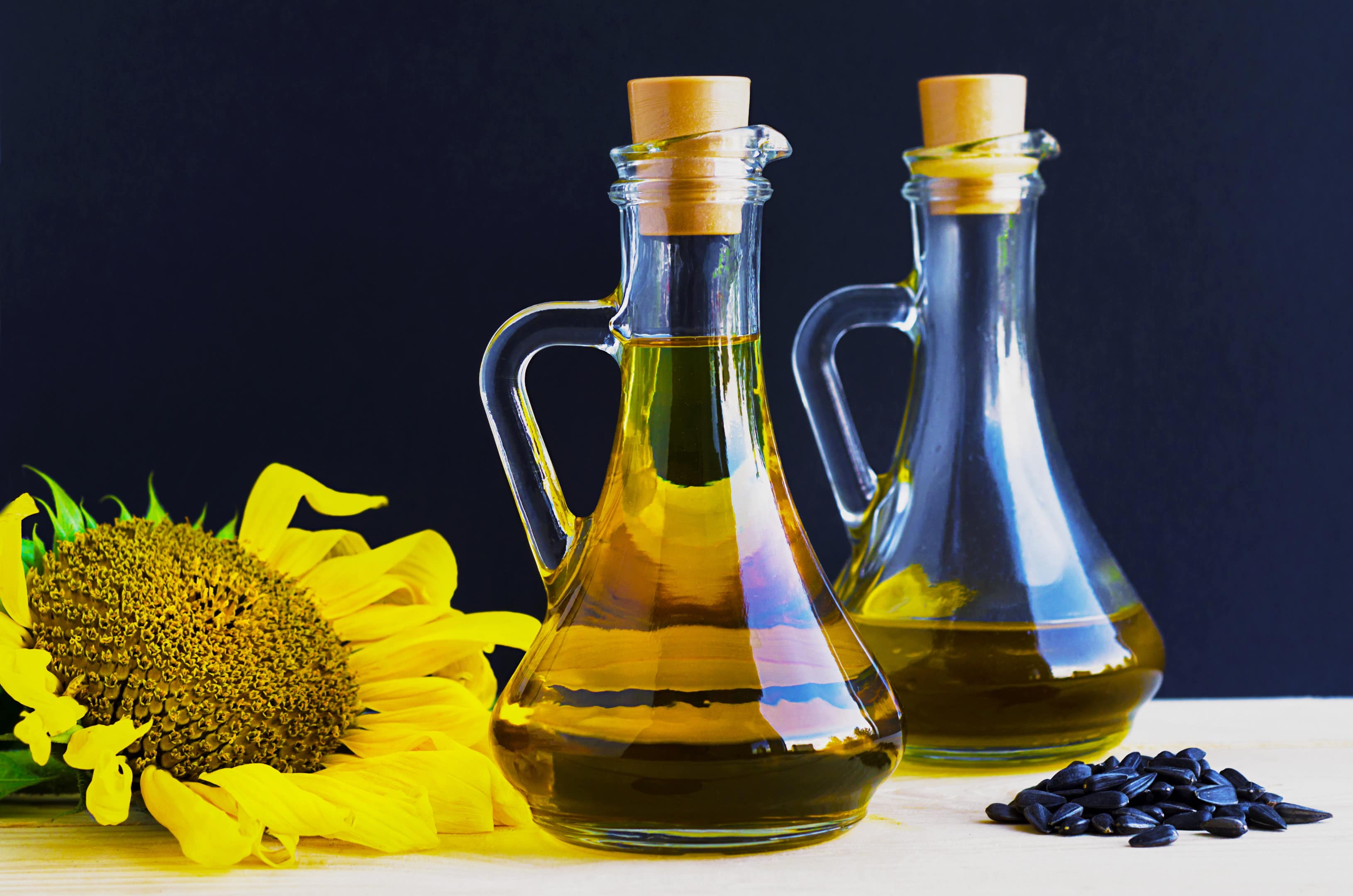 Sunflower oil glass jugs with sunflower and sunflower seeds on table