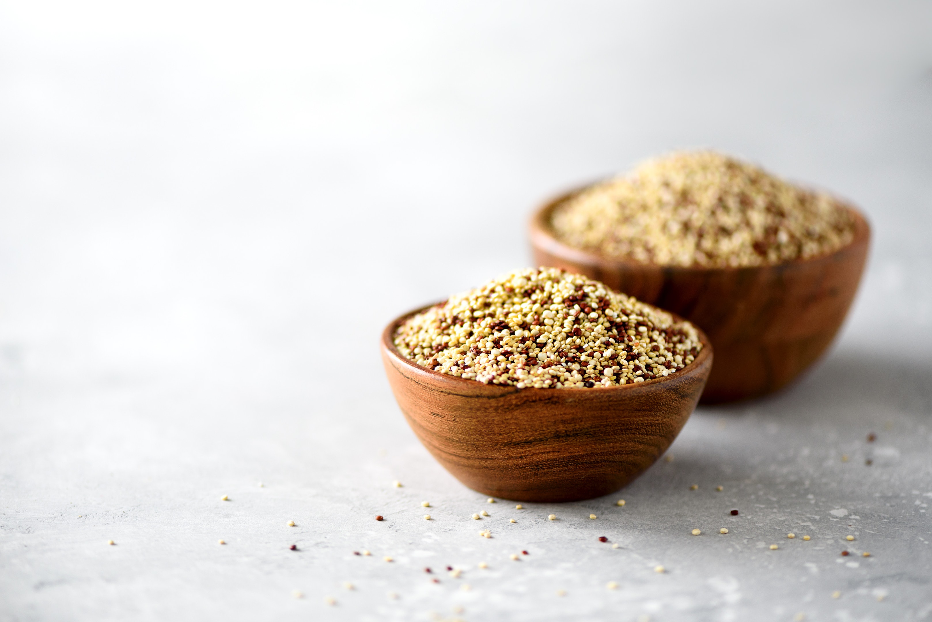 White and red raw quinoa in wooden bowls