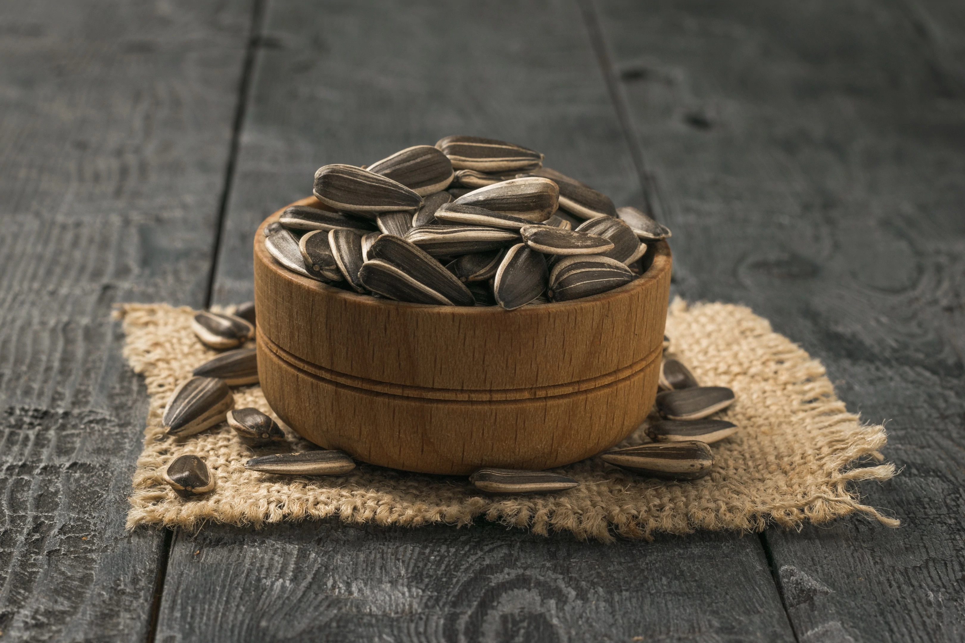 Wooden bowl with sunflower seeds on wooden table
