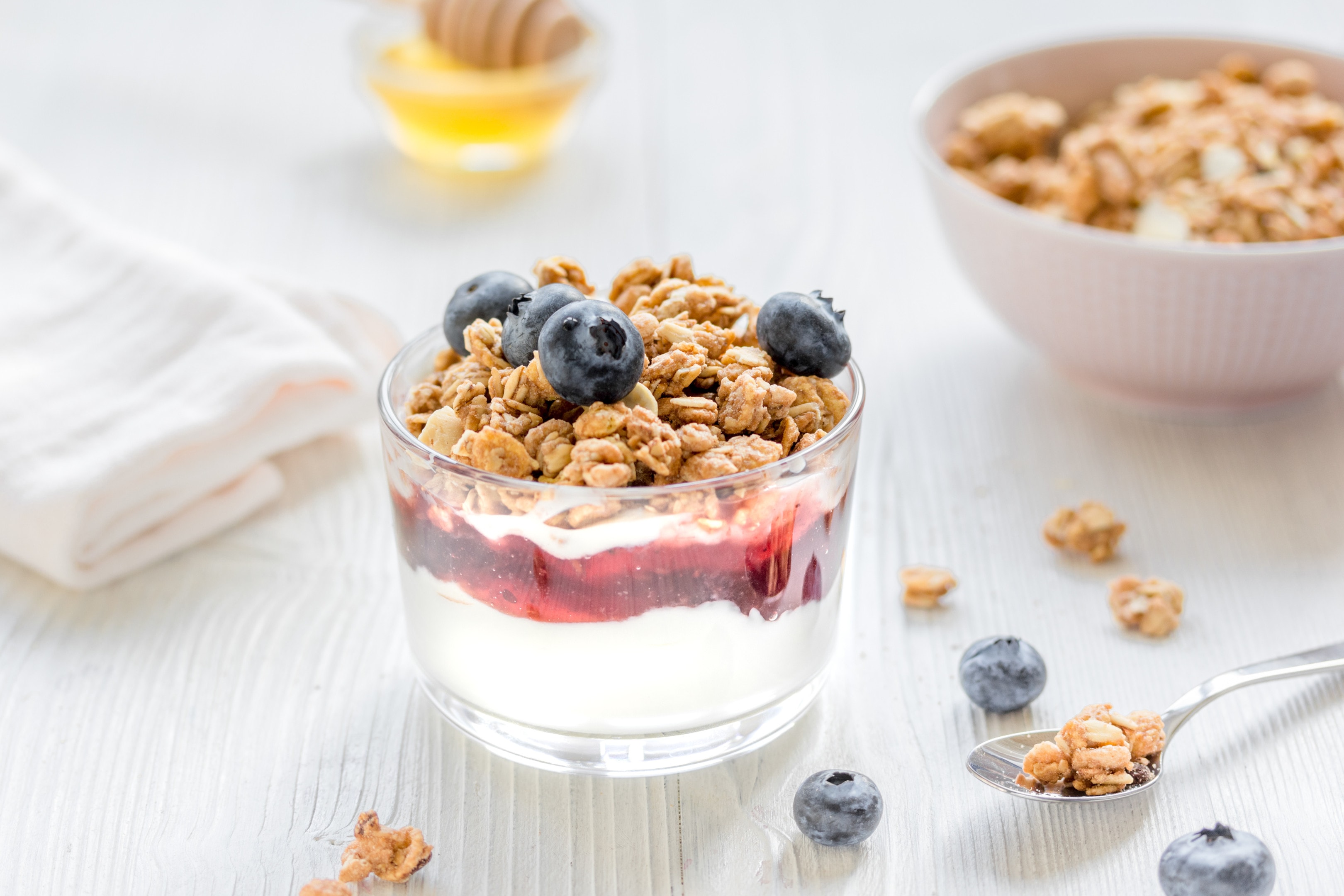 Yogurt with honey and berries on white table