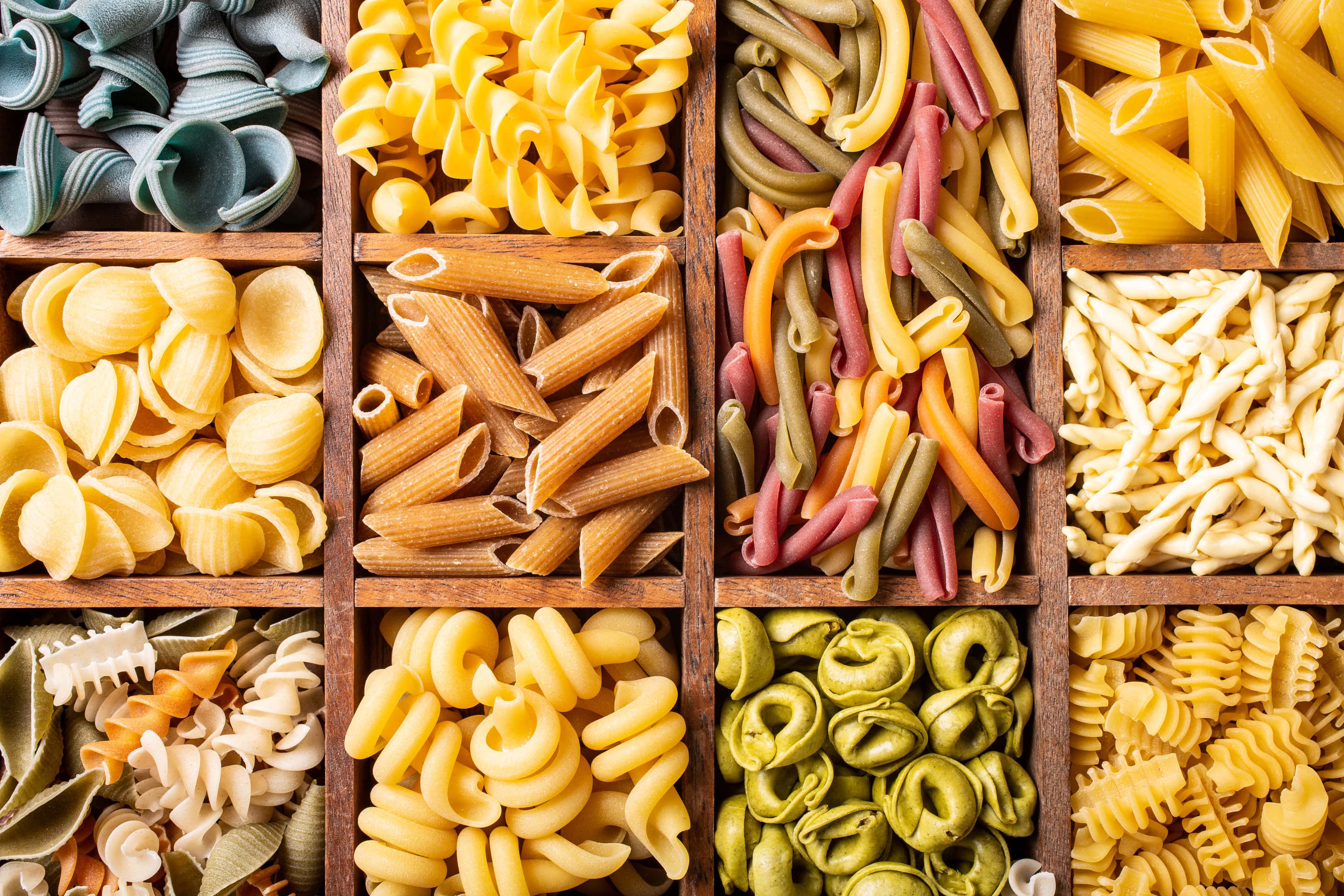 Assorted colorful Italian pasta in wooden box