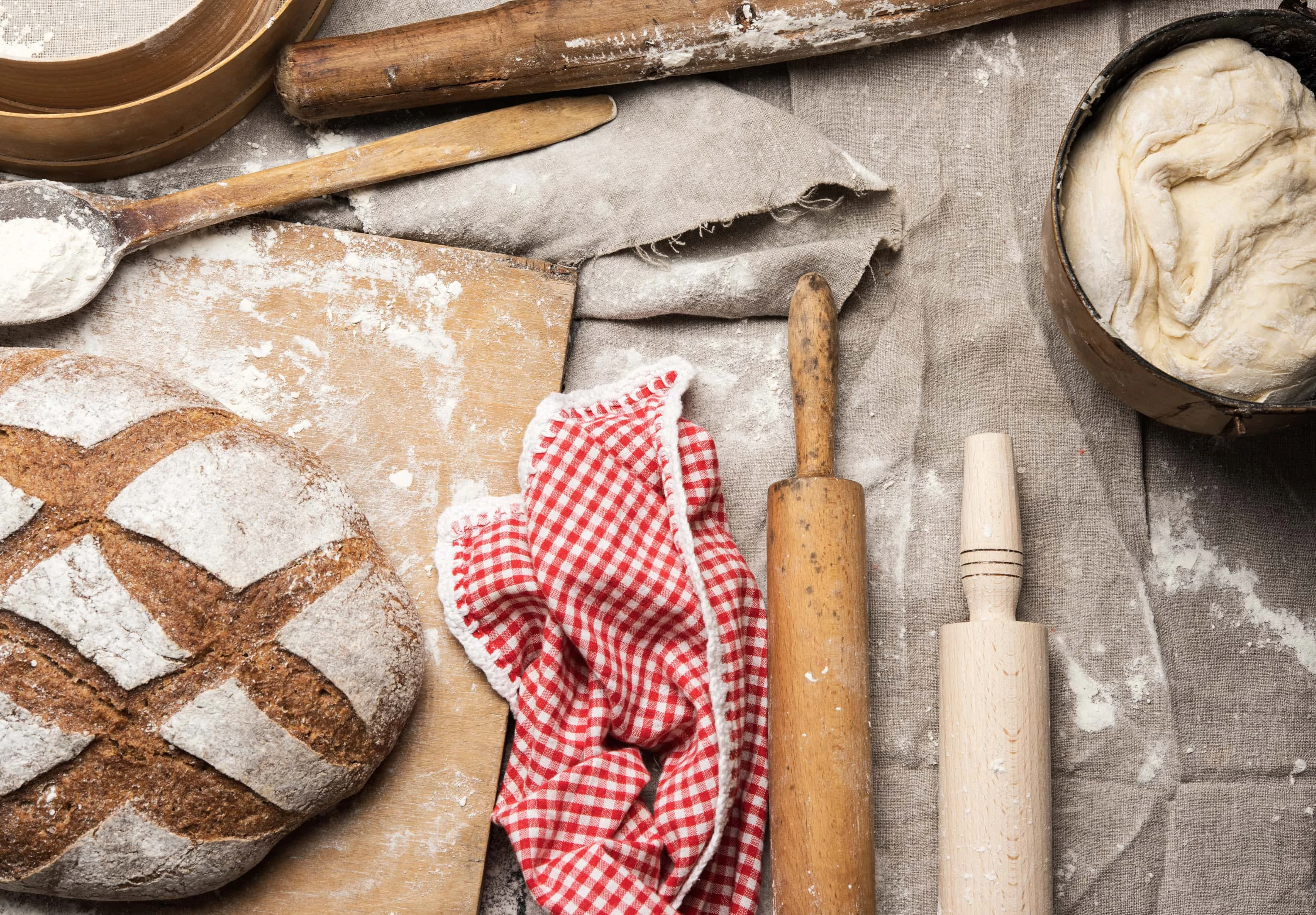 Bread lies on wooden board and yeast dough in metal bucket