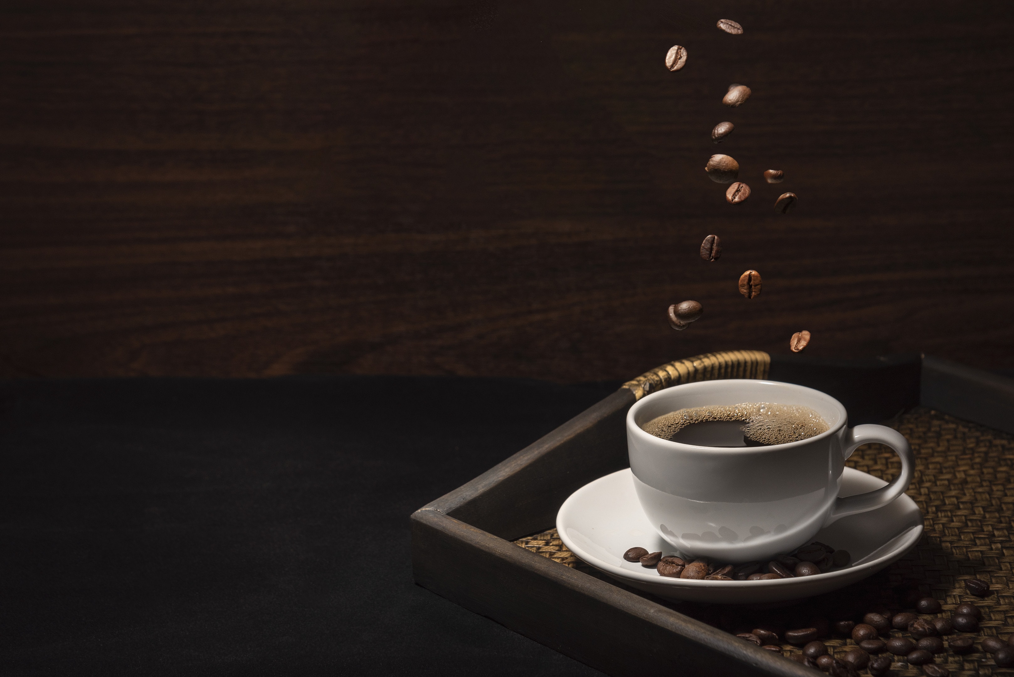 Coffee cup with coffee beans on bamboo tray