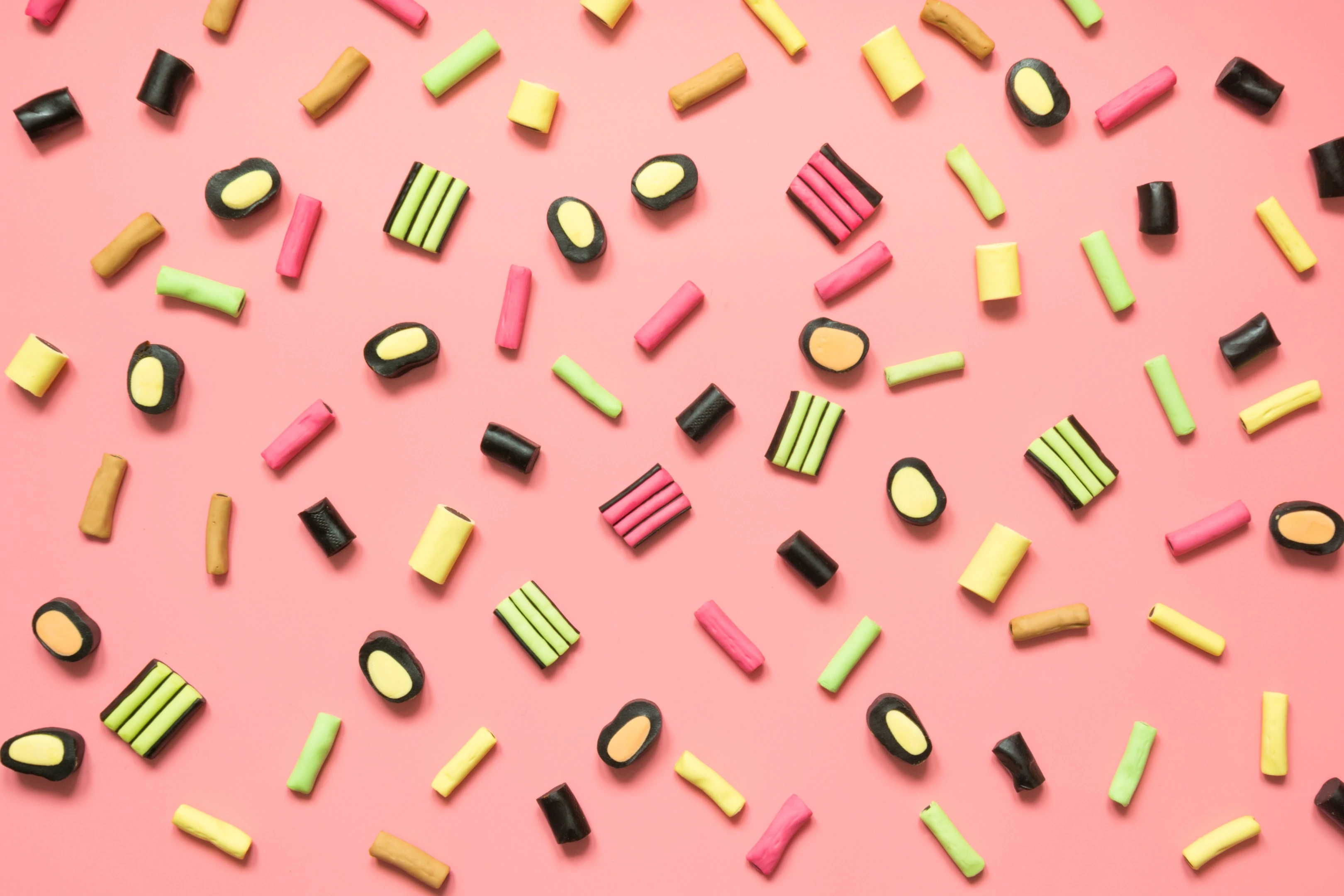 Colorful lollipop and licorice candy assortment on pink background