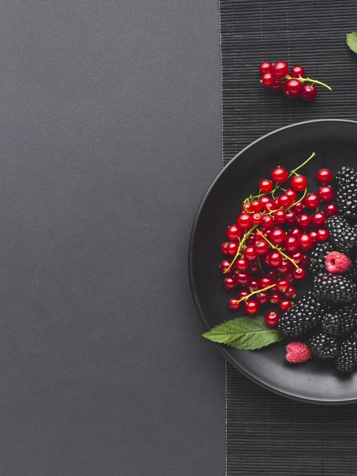 Flat lay plate of fresh berries on wooden table