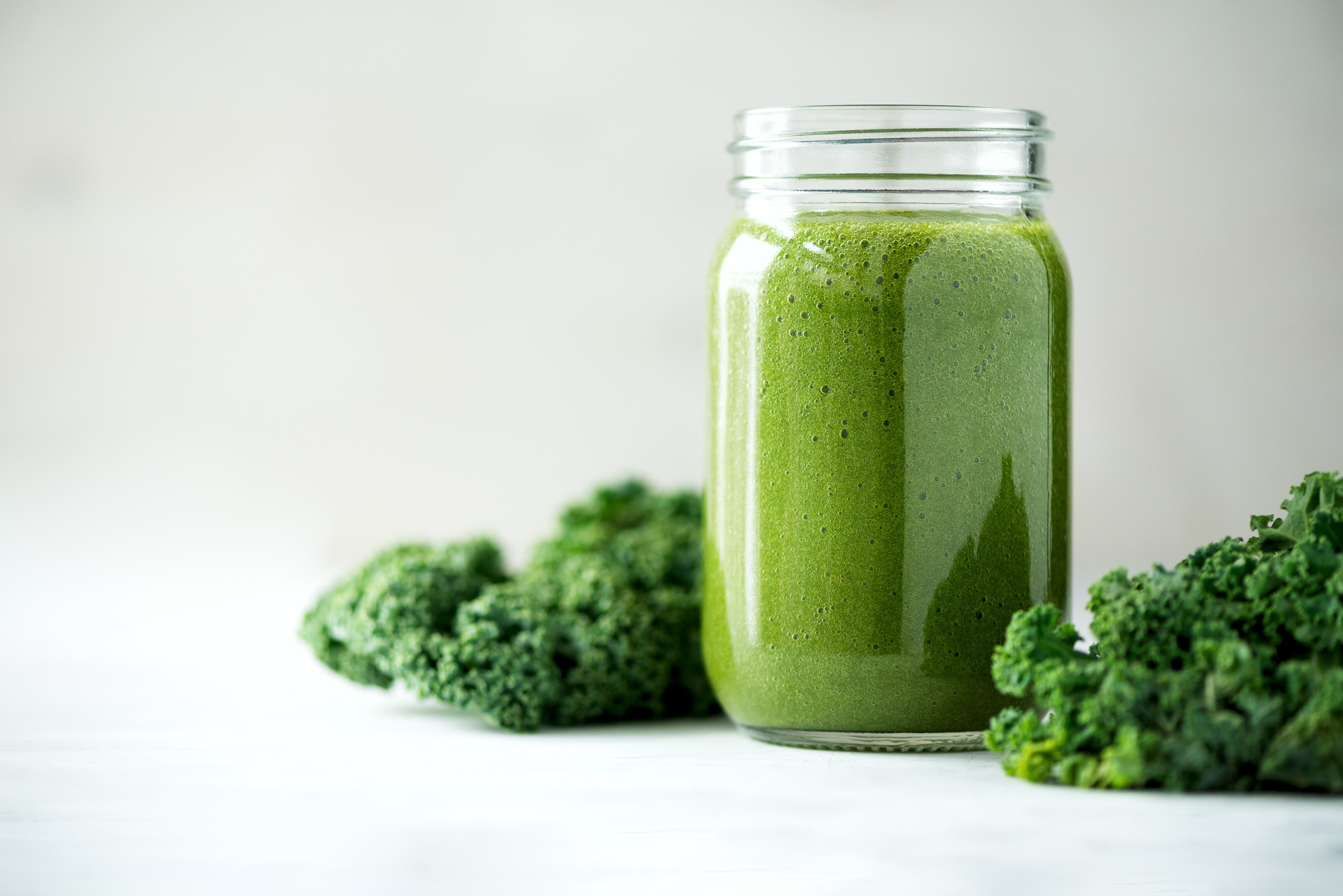 Glass jar with green smoothie of kale leaves lime apple kiwi grapes banana avocado lettuce