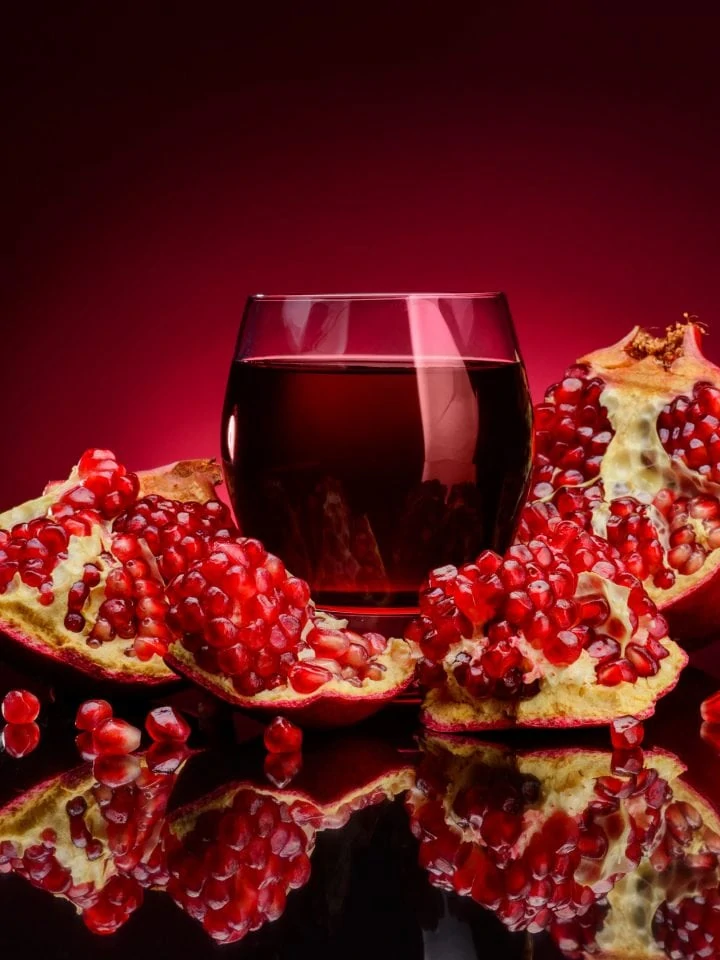 Pomegranate juice and fresh fruits on red background