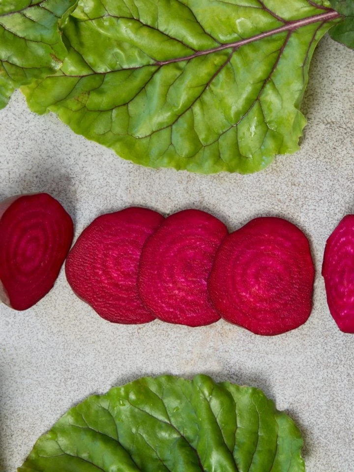 Raw beetroot sliced with leaves on rustic board