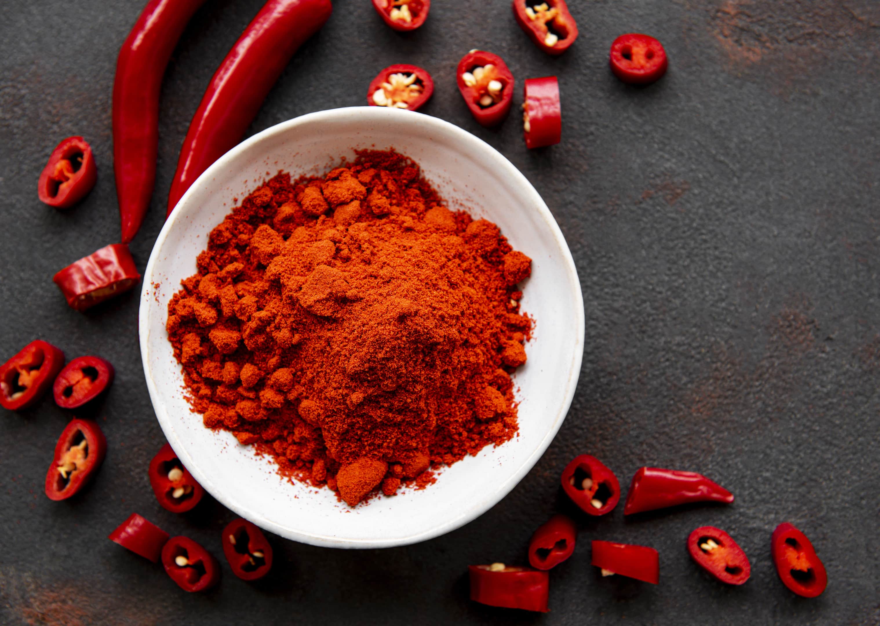 Red chili pepper powder and dried chilies on dark surface