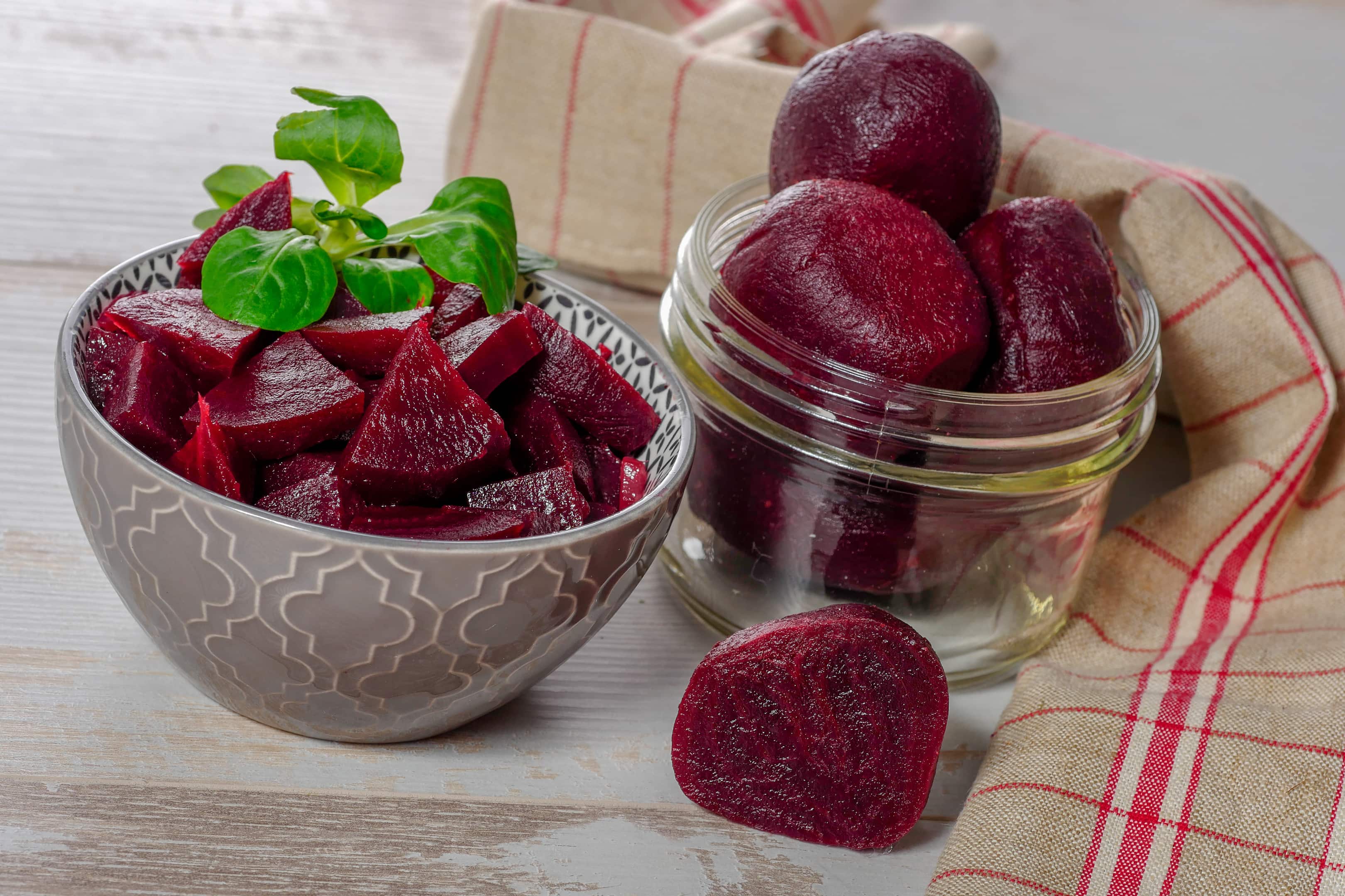 Red cooked beetroot in bowl on wooden table