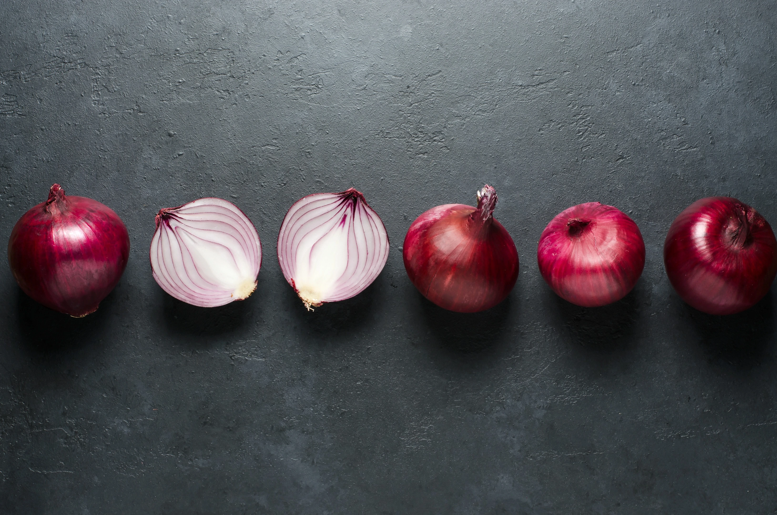 Red onion whole and sliced on black background