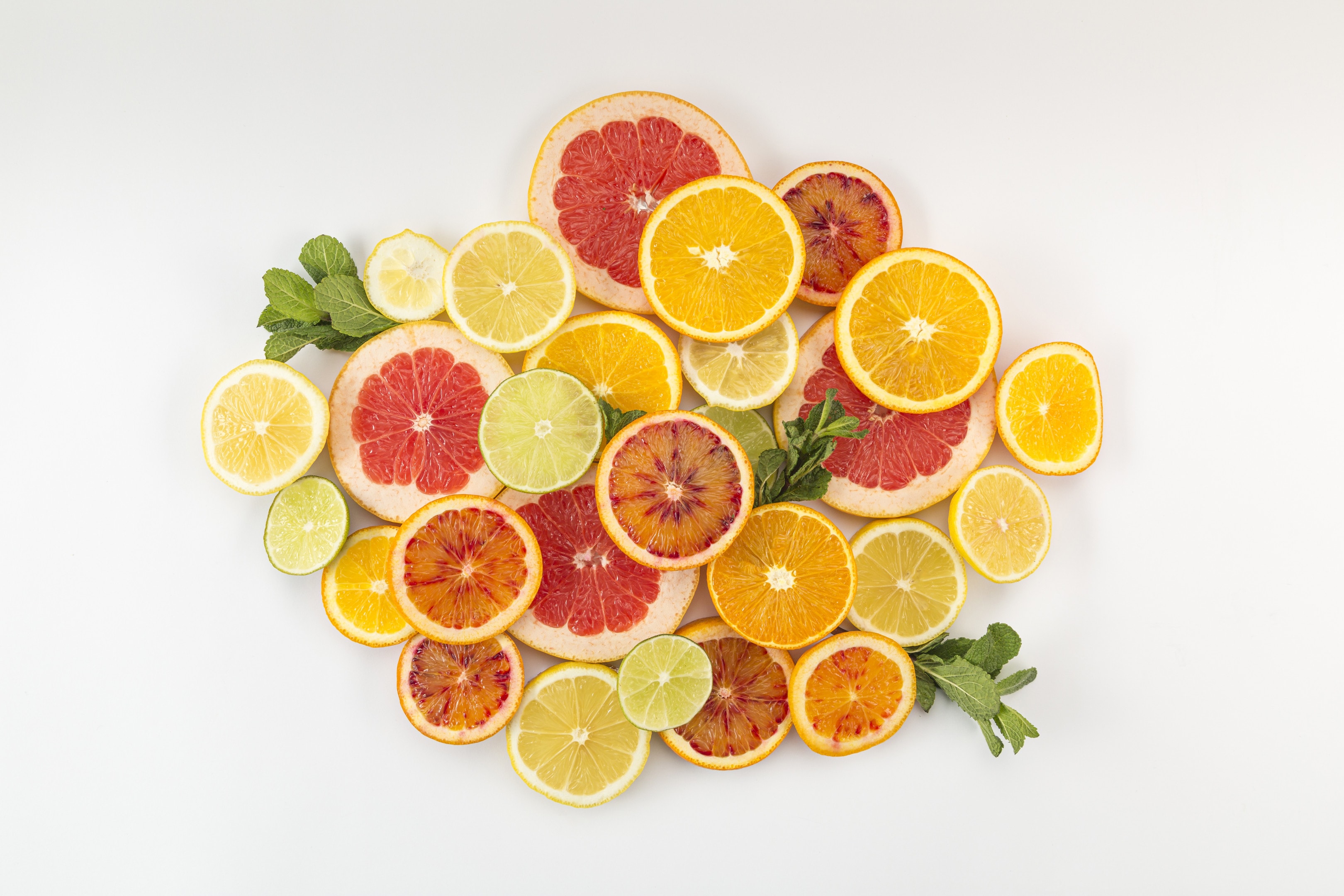 Slices citrus fruit pile of oranges lemons and grapefruits on white background