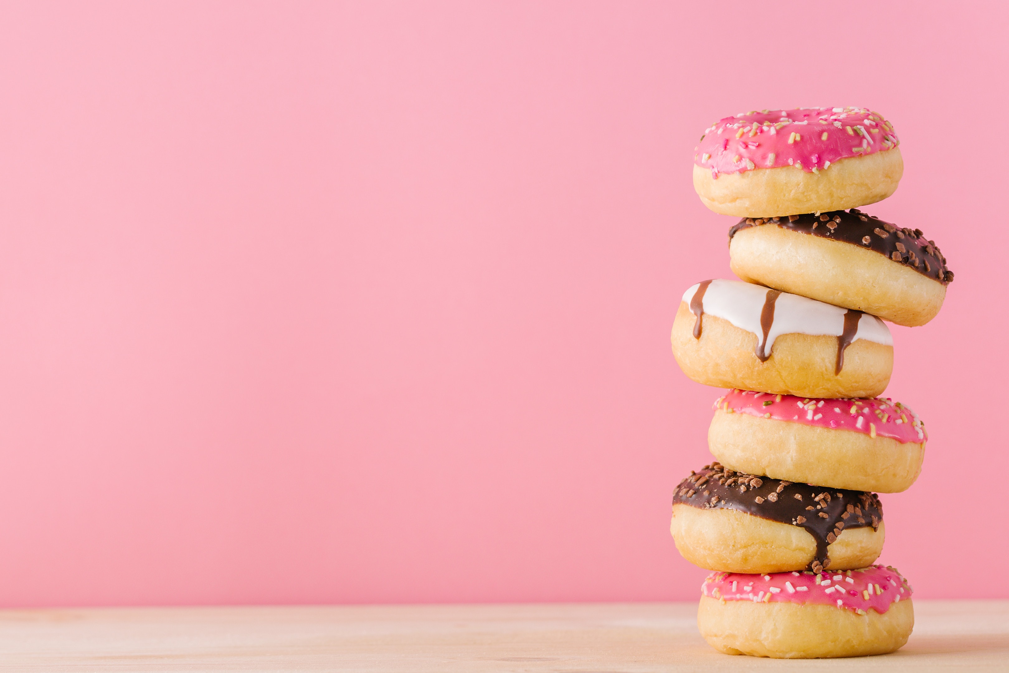 Stack of different donuts on pink background