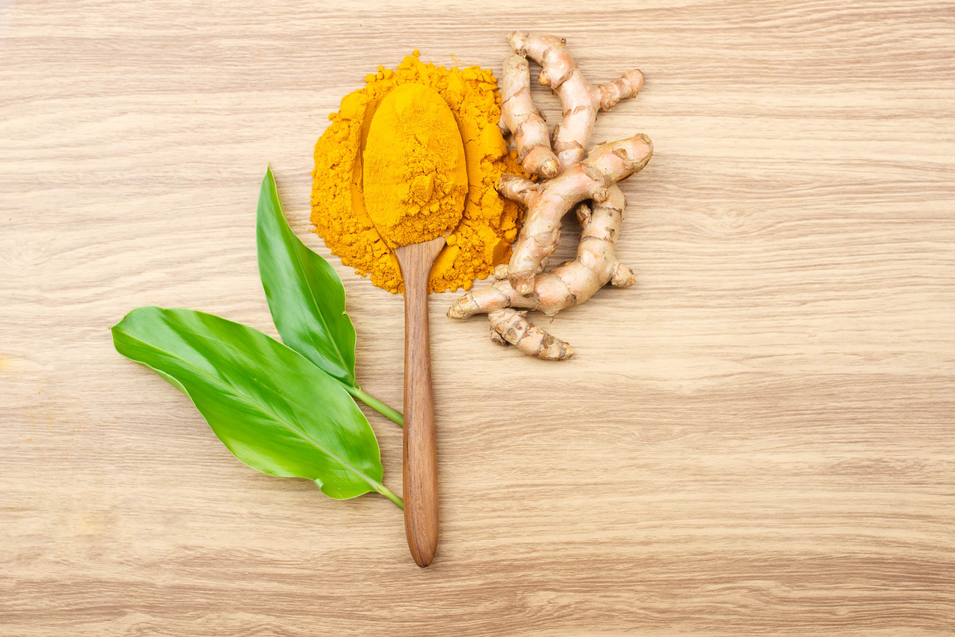 Turmeric root and powder on wooden table