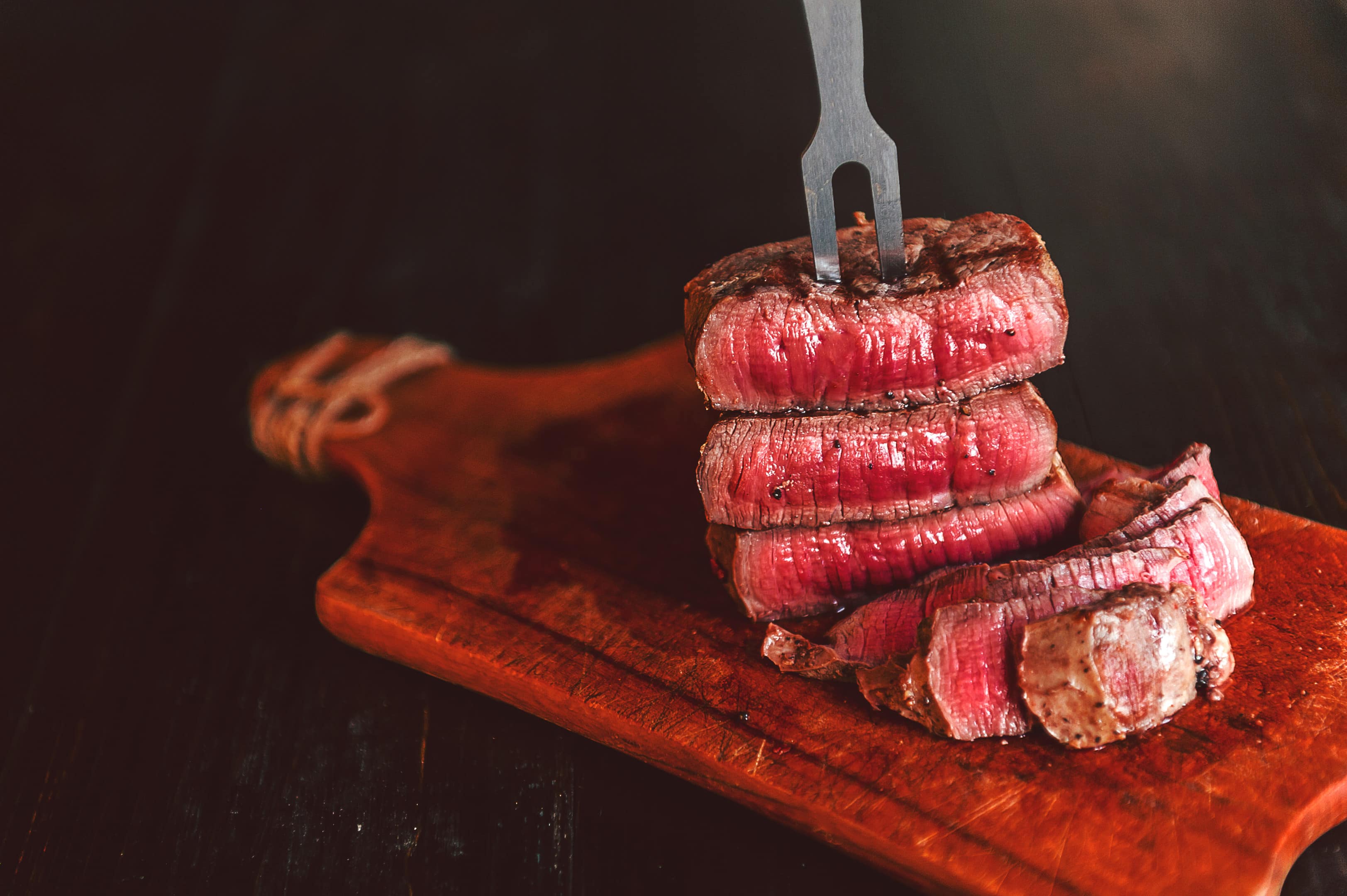 Beef steak with fork on wooden board