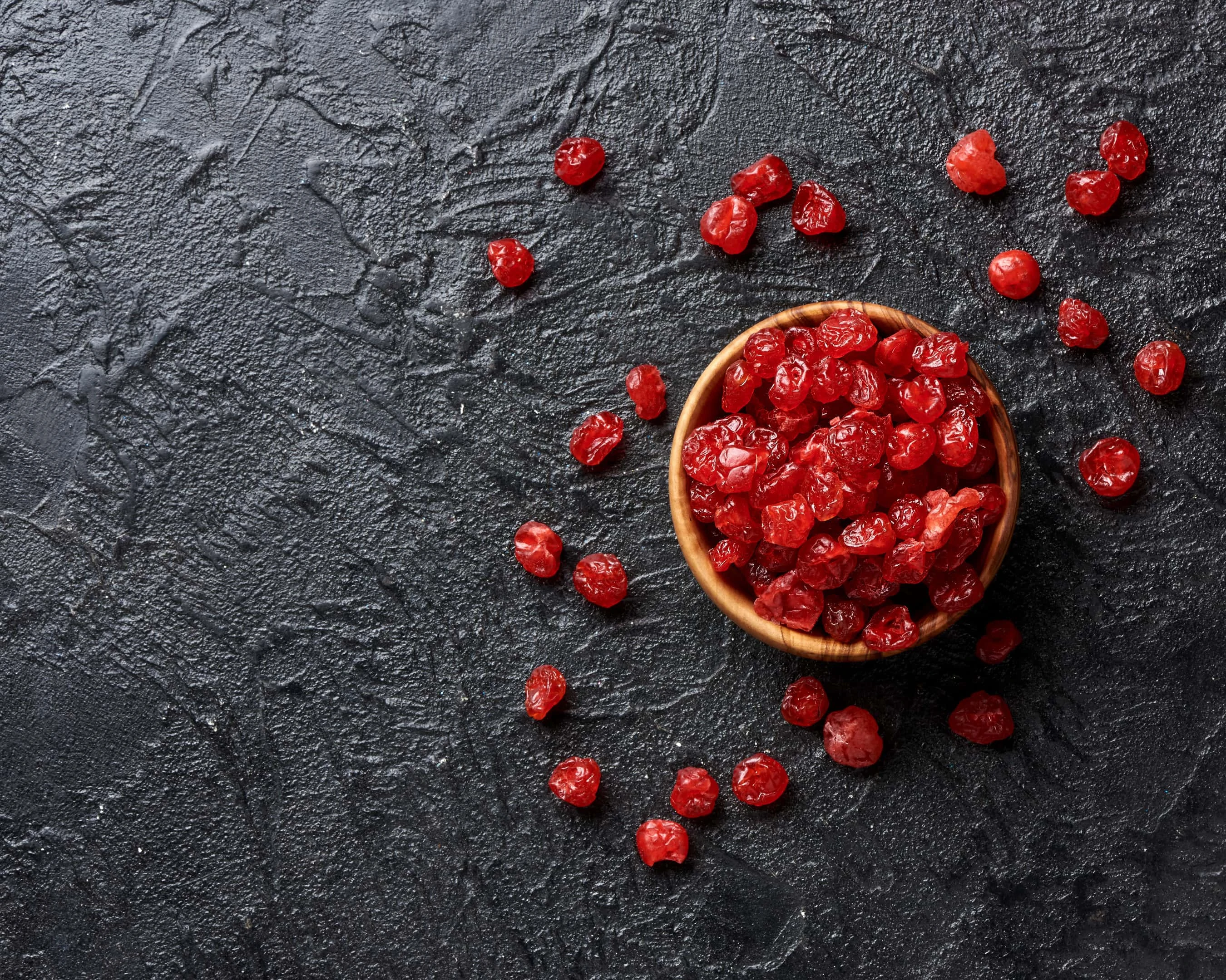 Dried red cherries on black surface