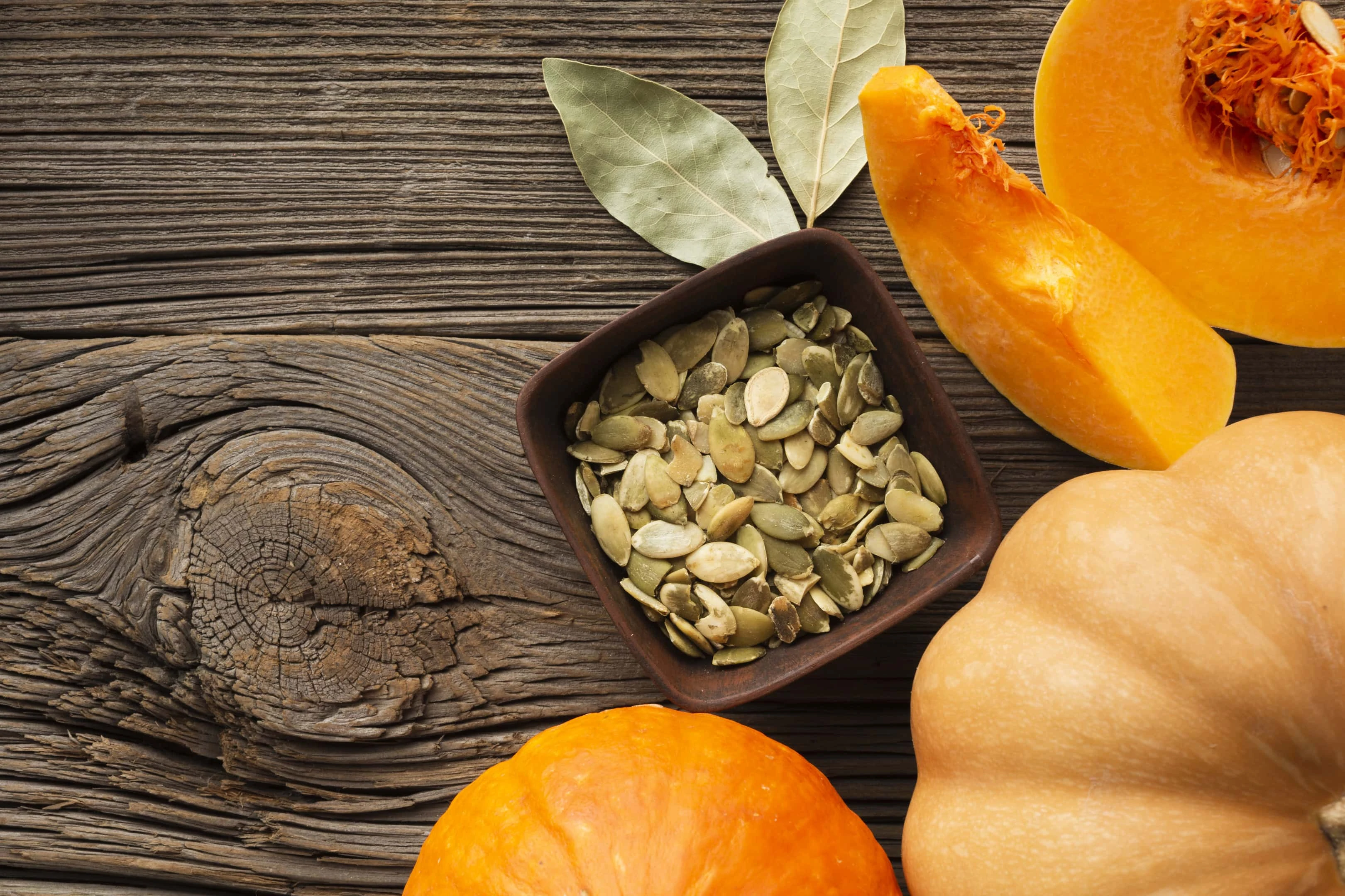 Pumpkin seeds with pumpkins on wooden table