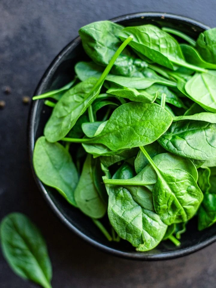 Spinach leaves in ceramic plate on kitchen table