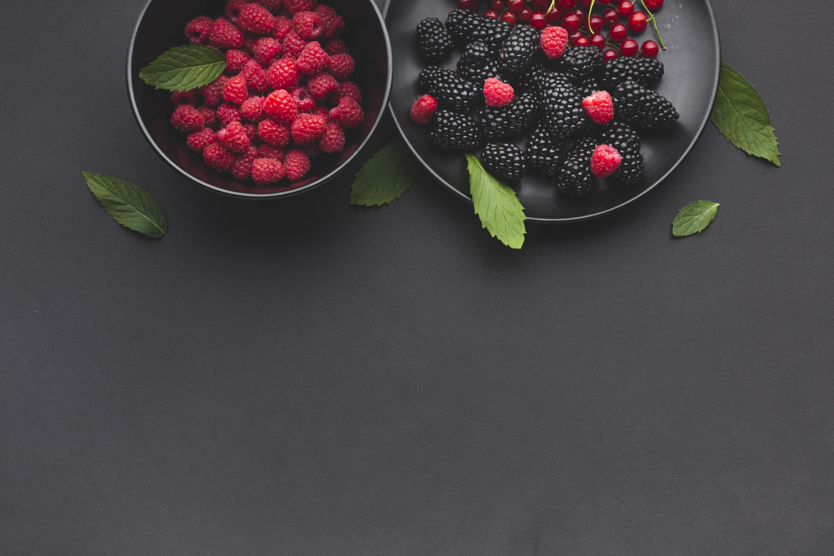 Plate and Bowl of Fresh Berries on Dark Table