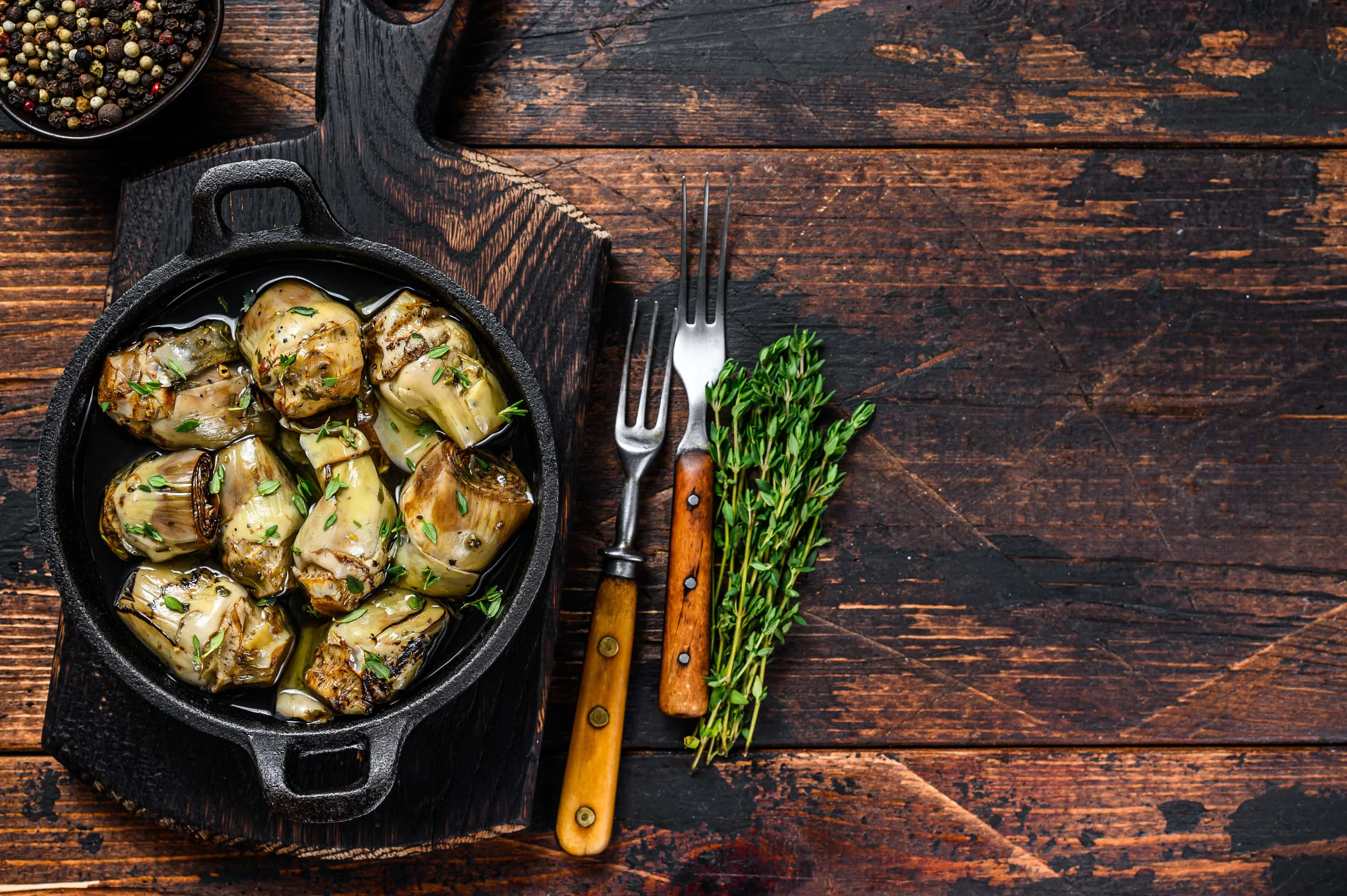 Artichokes marinated with champagne vinegar in pan on wooden table