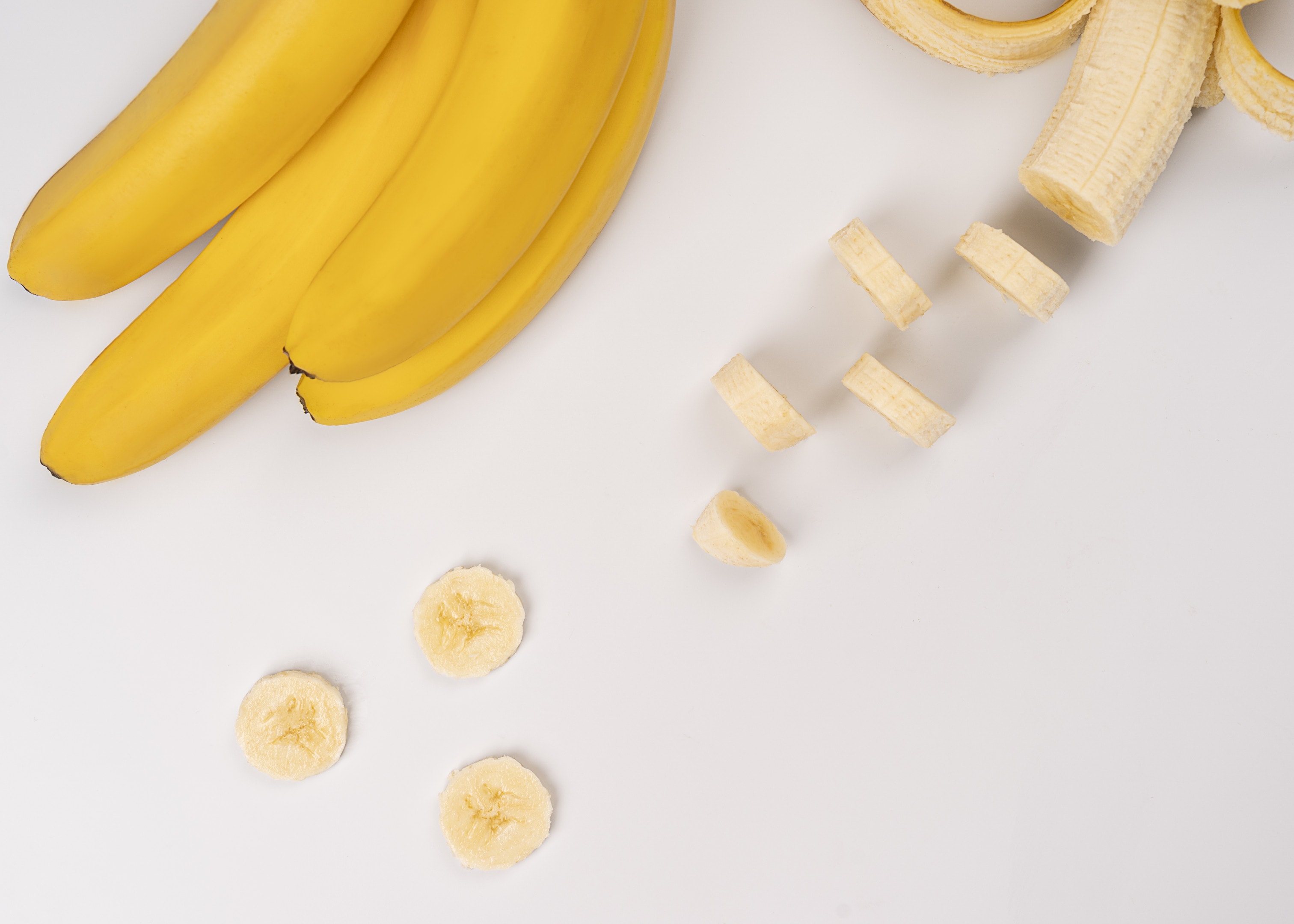 Bananas and banana slices on white table