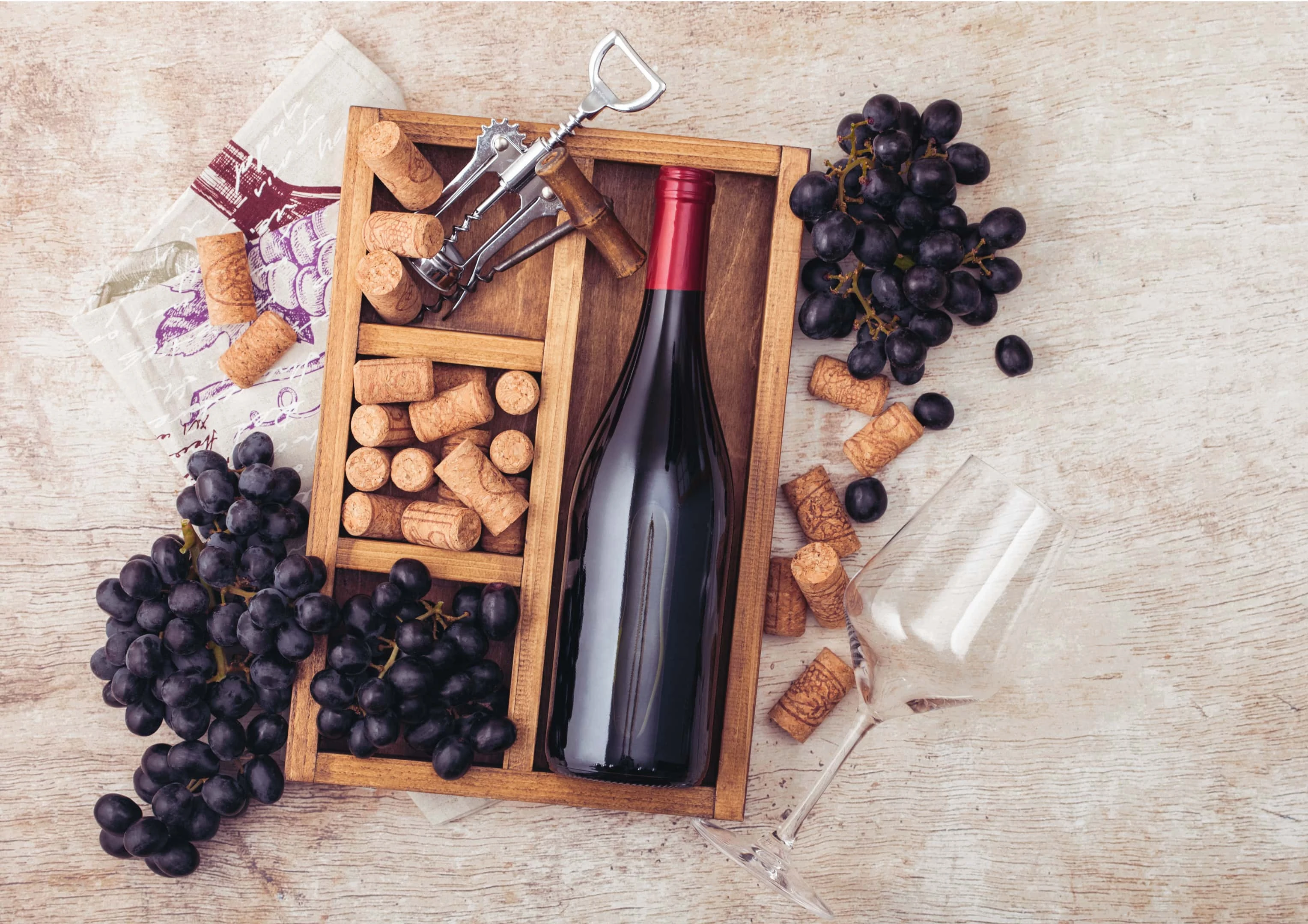 Bottle of red wine with corks and grapes in wooden box