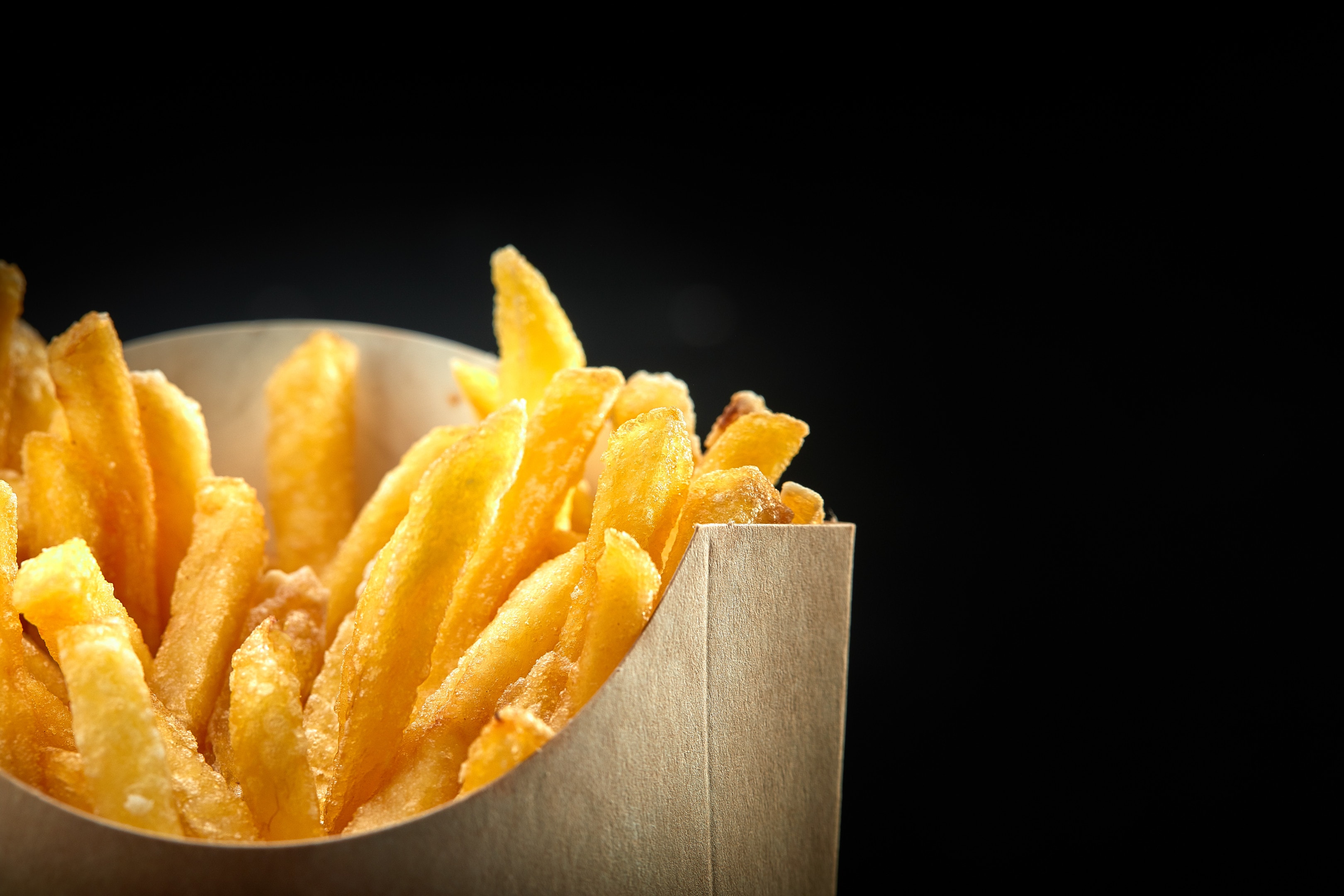 French fries in paper bag on black background