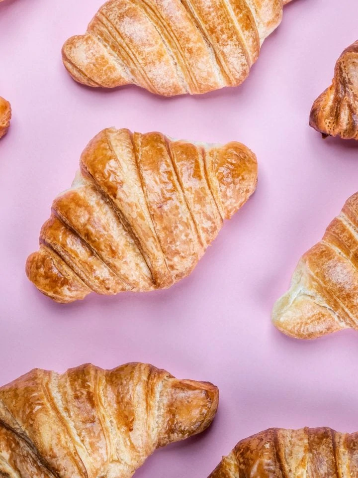 Freshly baked croissants on pink background