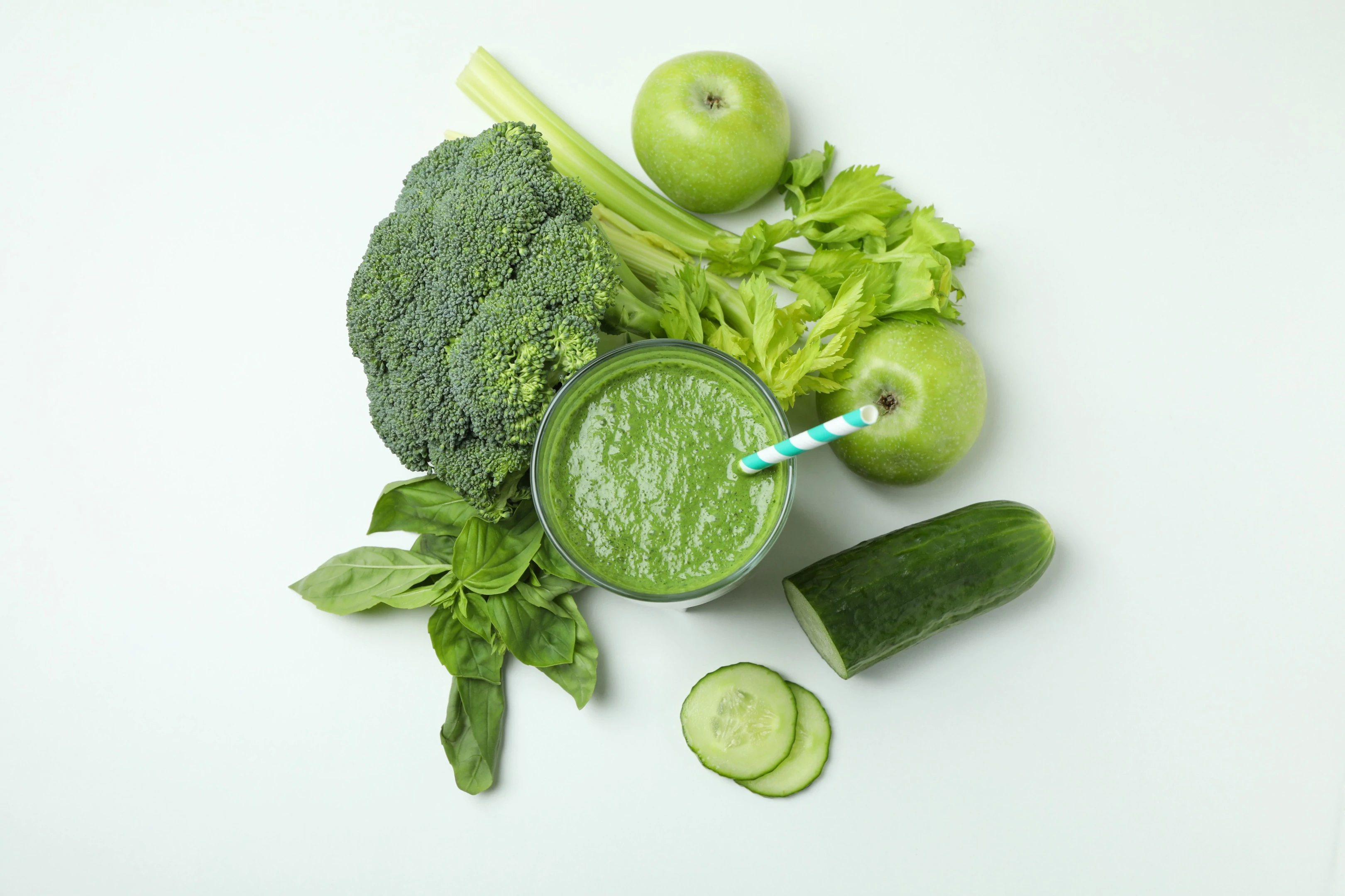 Glass of green smoothie and green leafy vegetable on white background