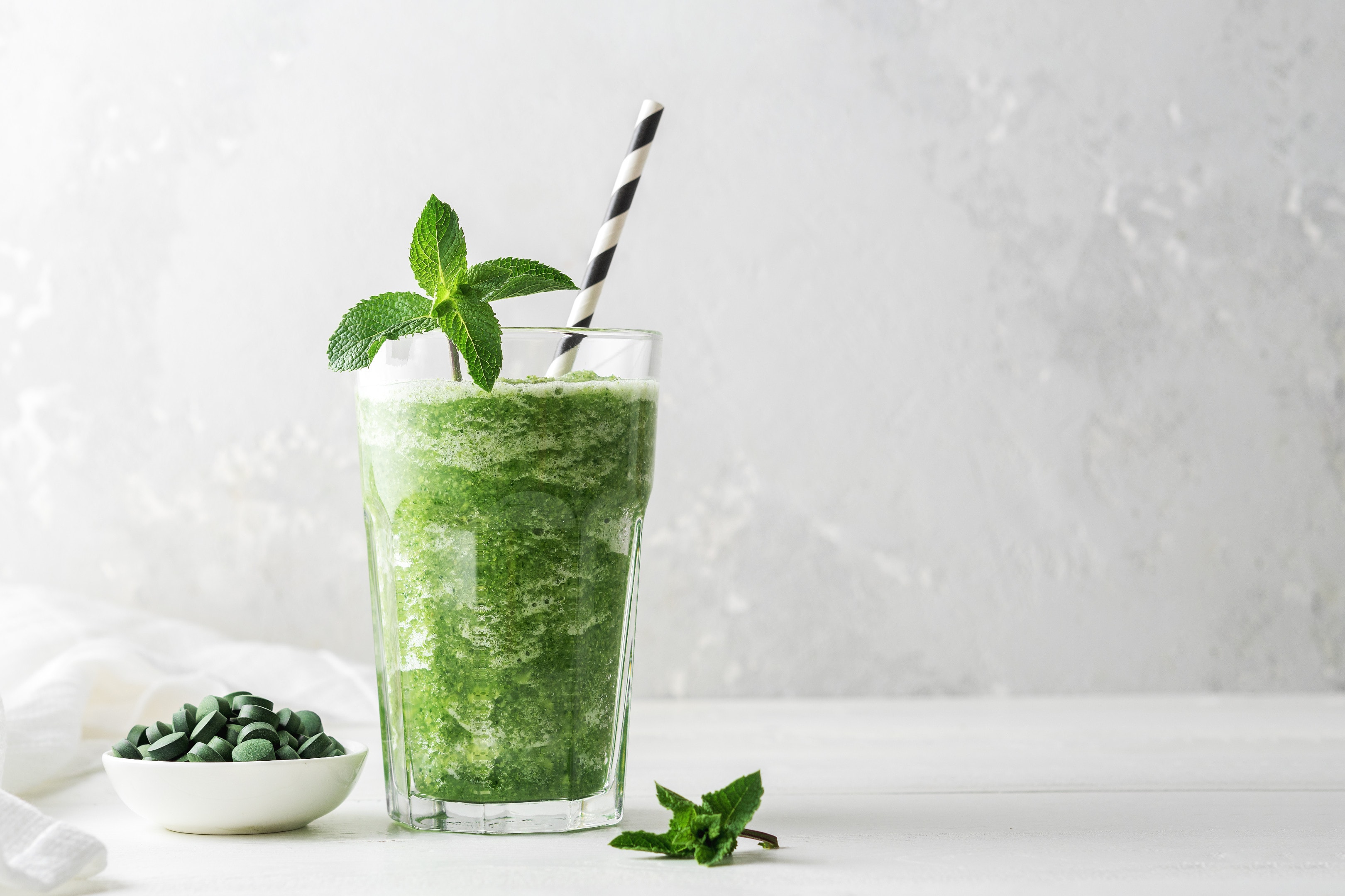 Glass of smoothies with addition chlorella spirulina with mint grey on concrete background