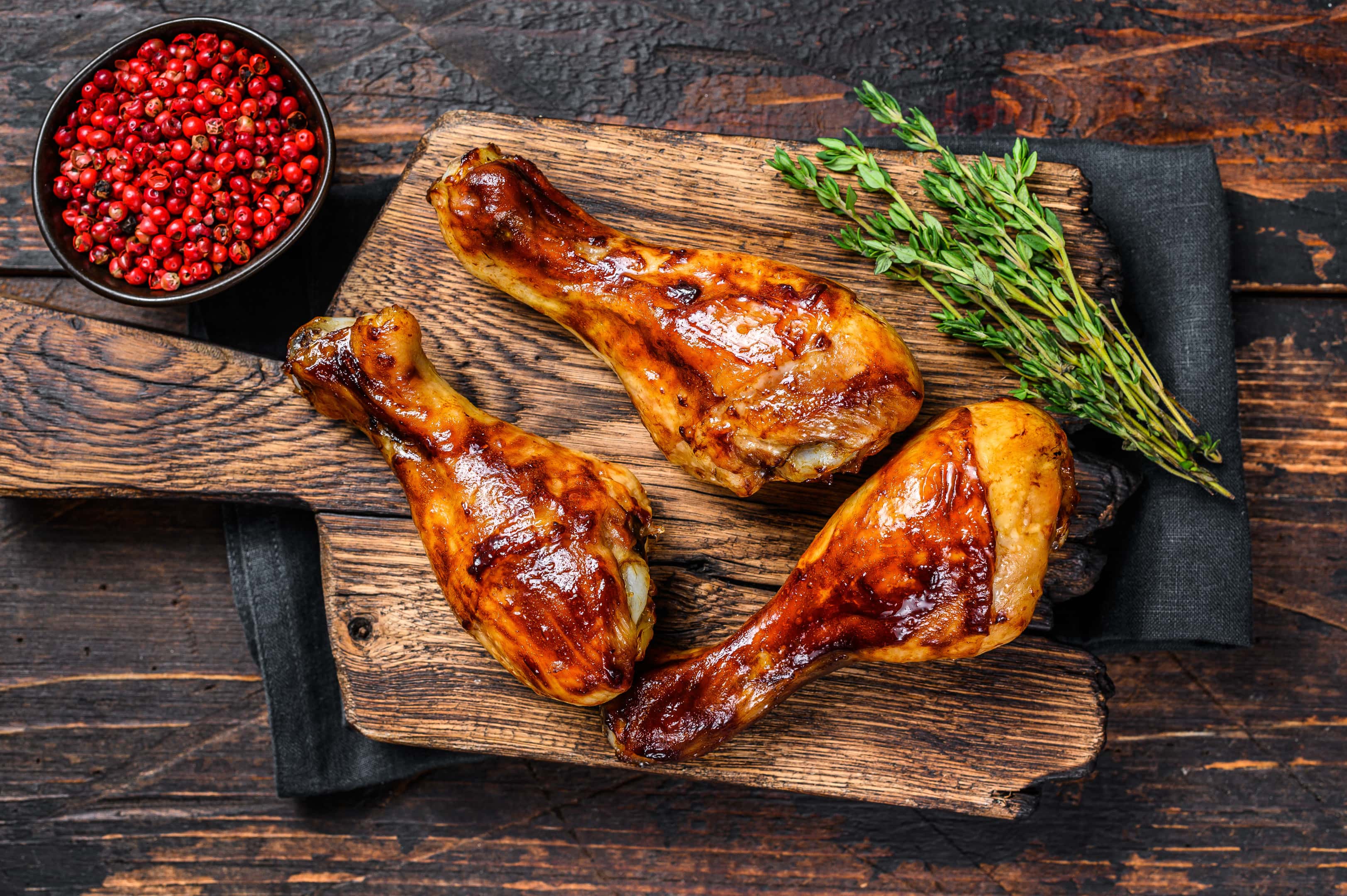 Grilled chicken drumsticks glazed with malt vinegar on wooden cutting board