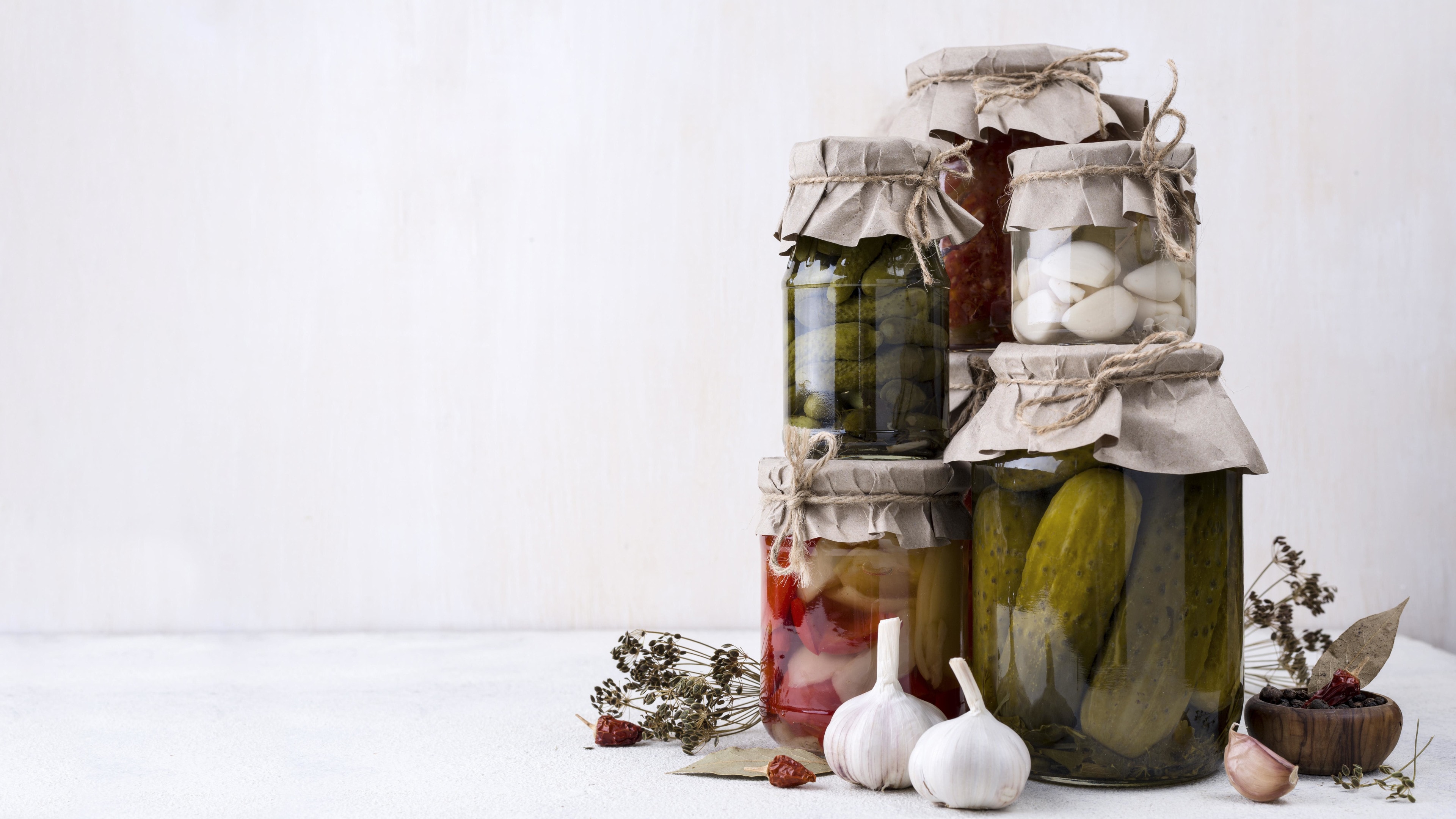 Jars assortment with picked vegetables on white table